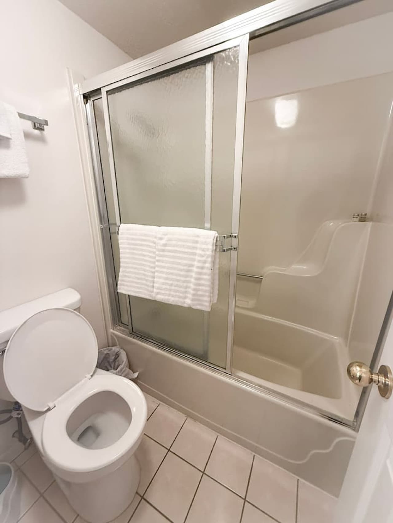 Relax in a spotless, well-lit bathroom featuring a spacious shower and fresh linens for a comfortable stay. Perfect for guests seeking cleanliness, convenience, and a hotel-style experience.