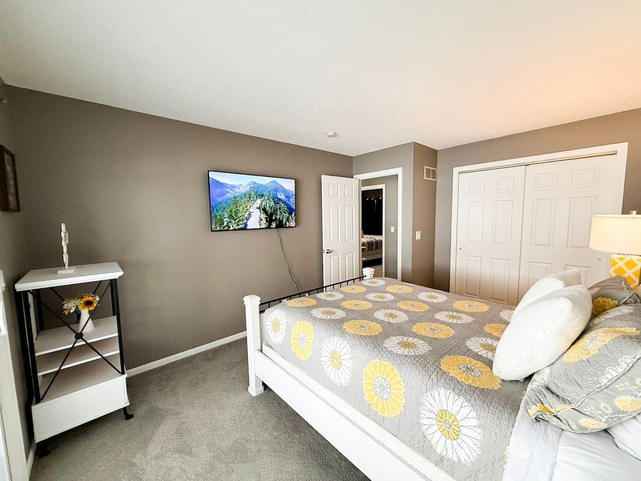 Bright guest room with large closets and mounted TV.