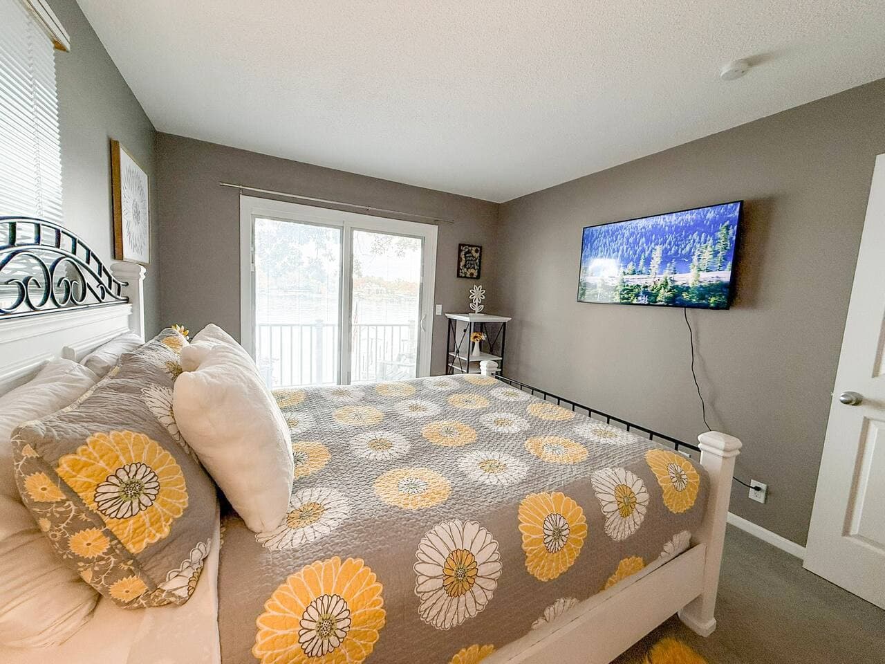 Sunny bedroom with TV and cheerful yellow-pattern bedding.