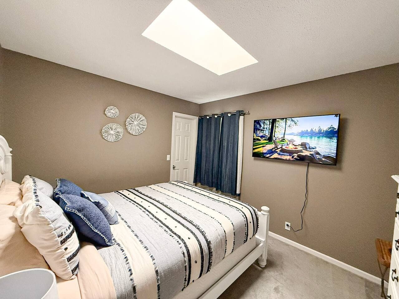 Bright bedroom with skylight, TV, and soft neutral tones.