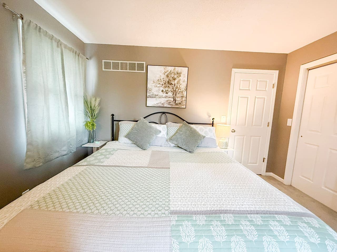 Bright king bedroom with large windows and relaxing ambiance.
