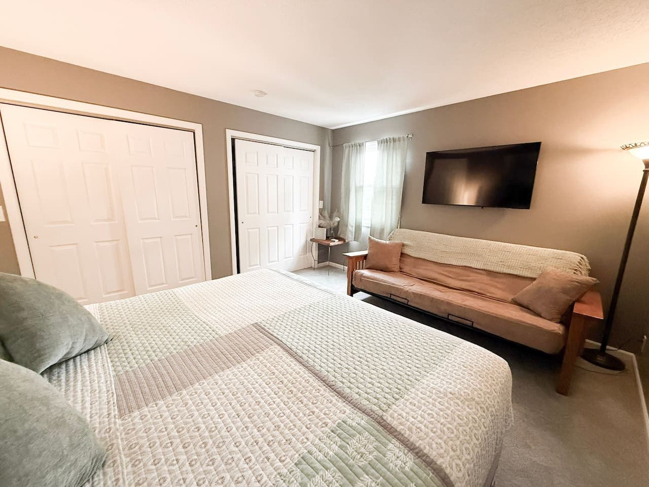 Spacious bedroom with TV and comfy sofa.