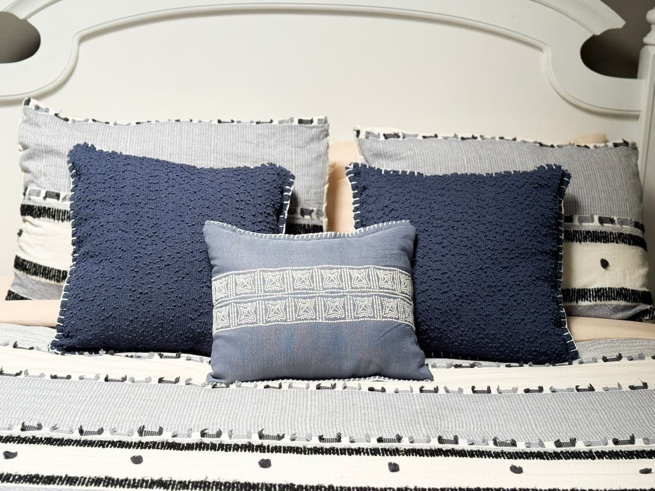 Close-up of comfortable bedding with decorative pillows in blue and white.