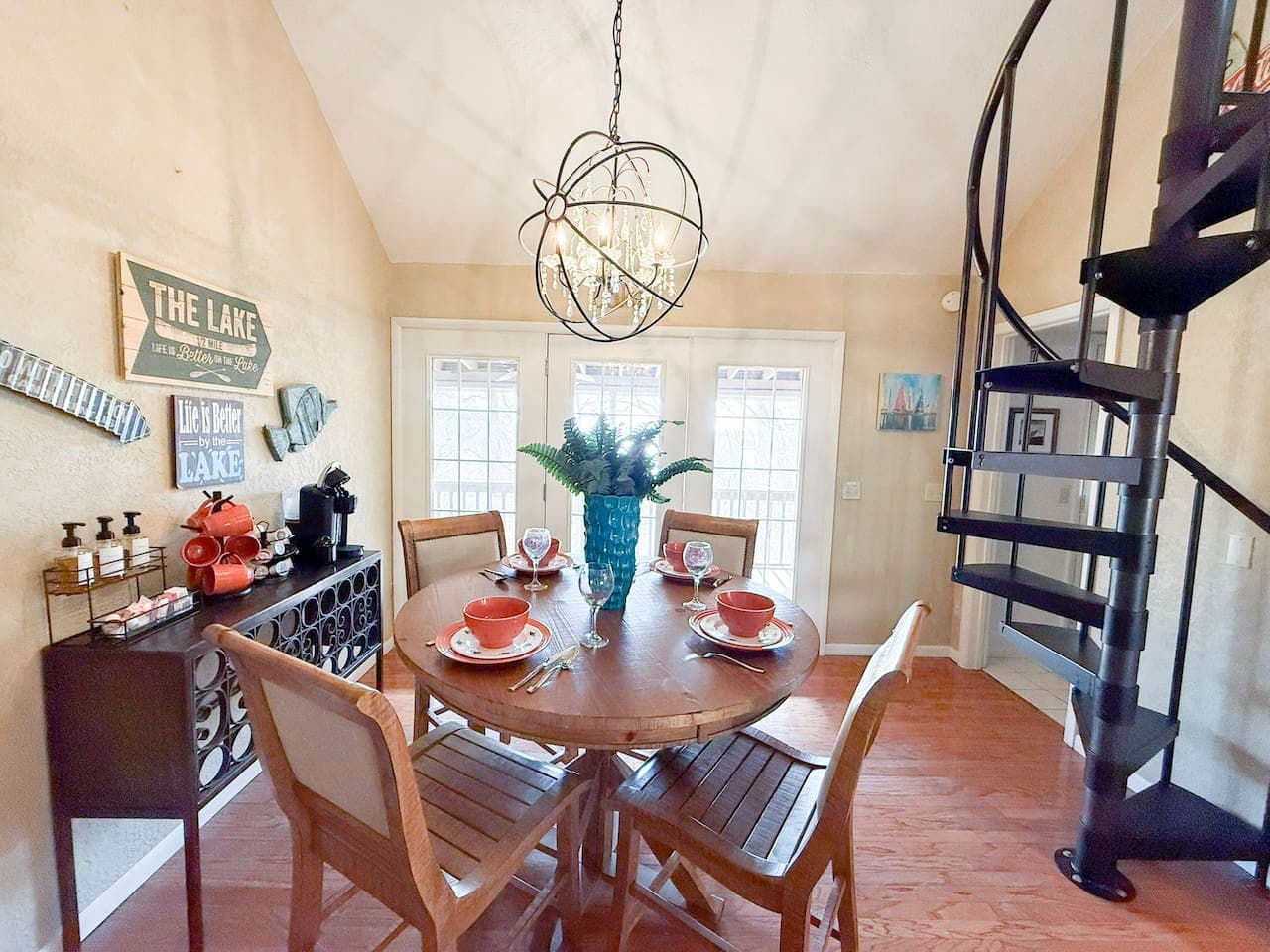 Gather for meals in a bright, lake-inspired dining area with stylish décor and a unique spiral staircase backdrop.