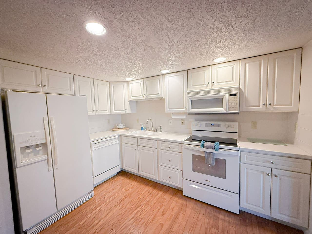 Beautifully maintained, all-white kitchen with generous counter space and fully stocked essentials for easy, enjoyable meals.