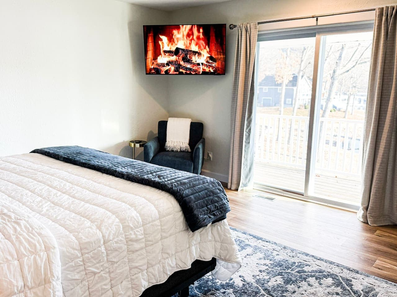 Relax in a spacious bedroom featuring a plush king bed, smart TV, and serene lake views through sliding glass doors.