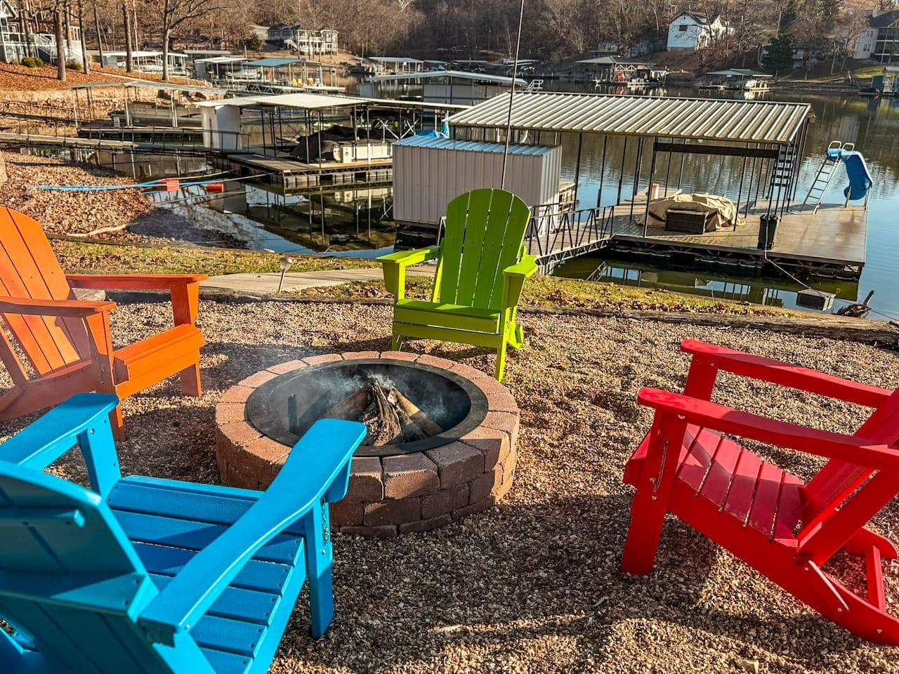 Gather around the lakeside fire pit with colorful Adirondack chairs, perfect for cozy nights and sunset views.