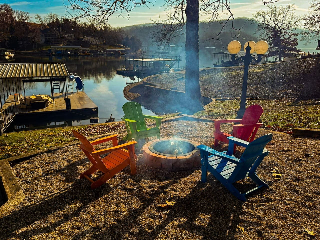 Gather by the lakeside fire pit with colorful Adirondack chairs, perfect for cozy evenings and scenic views.