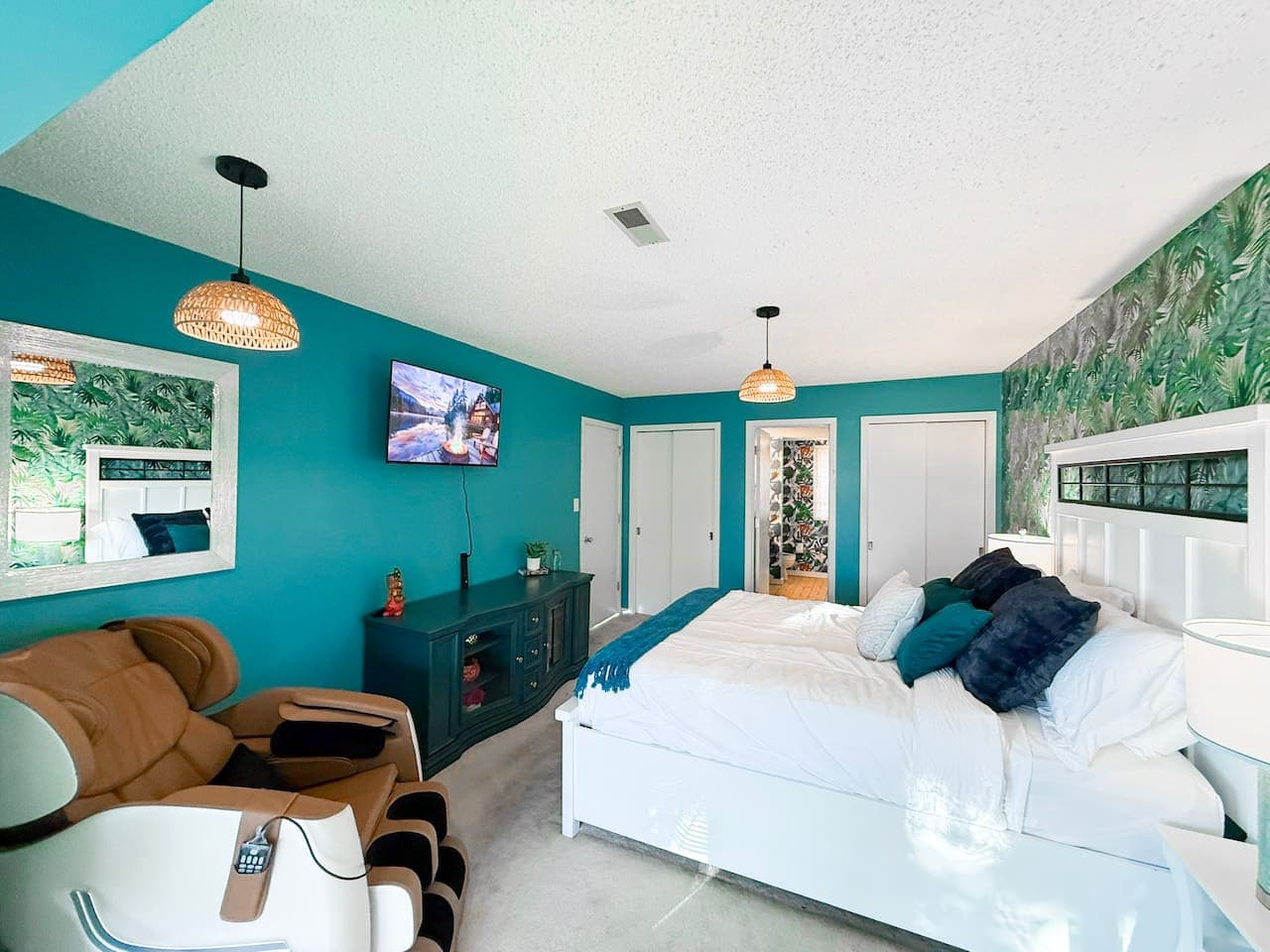 Bright bedroom with a large bed, TV, and massage chair.