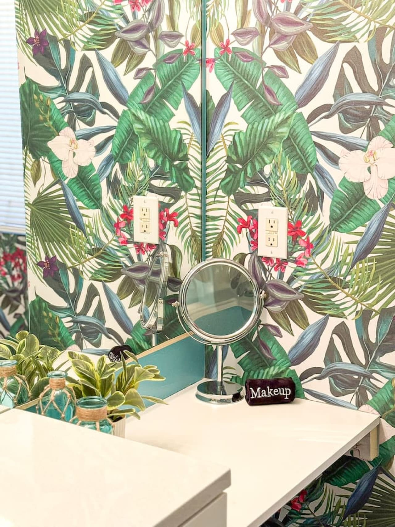 Lush tropical wallpaper and thoughtful details in the vanity area.