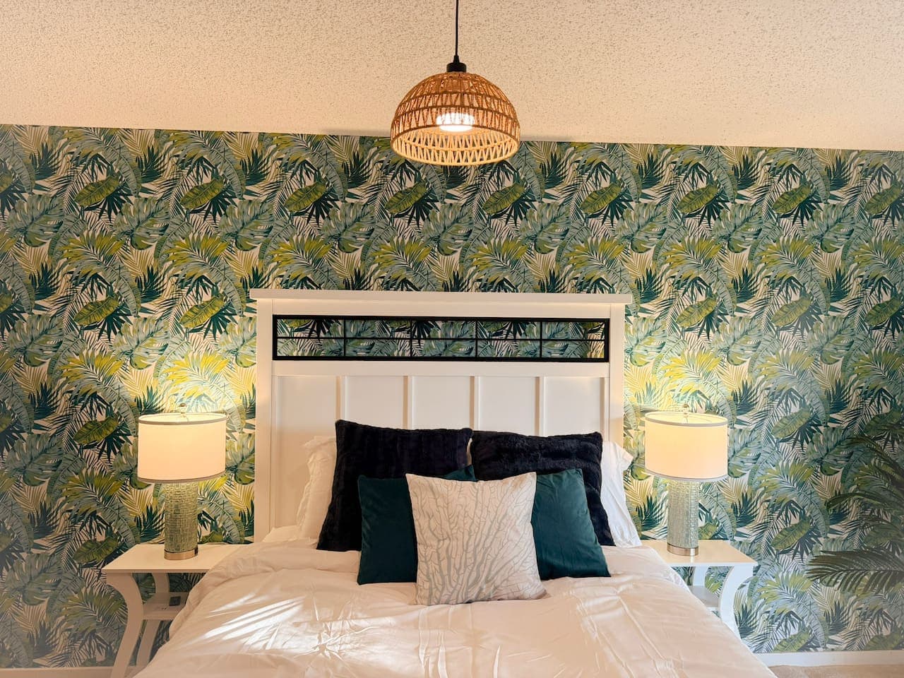 Close-up of comfortable bed with stylish tropical wallpaper.