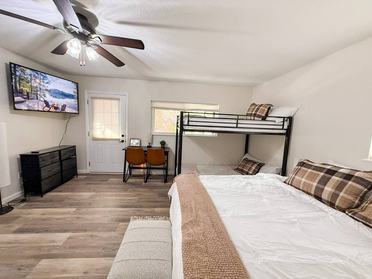 Spacious room with king bed, bunks, and TV.