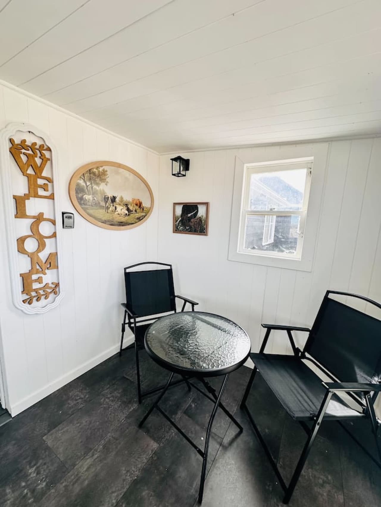 A bright and welcoming enclosed patio with vintage Western art and a cozy bistro set—ideal for morning coffee or evening conversation.