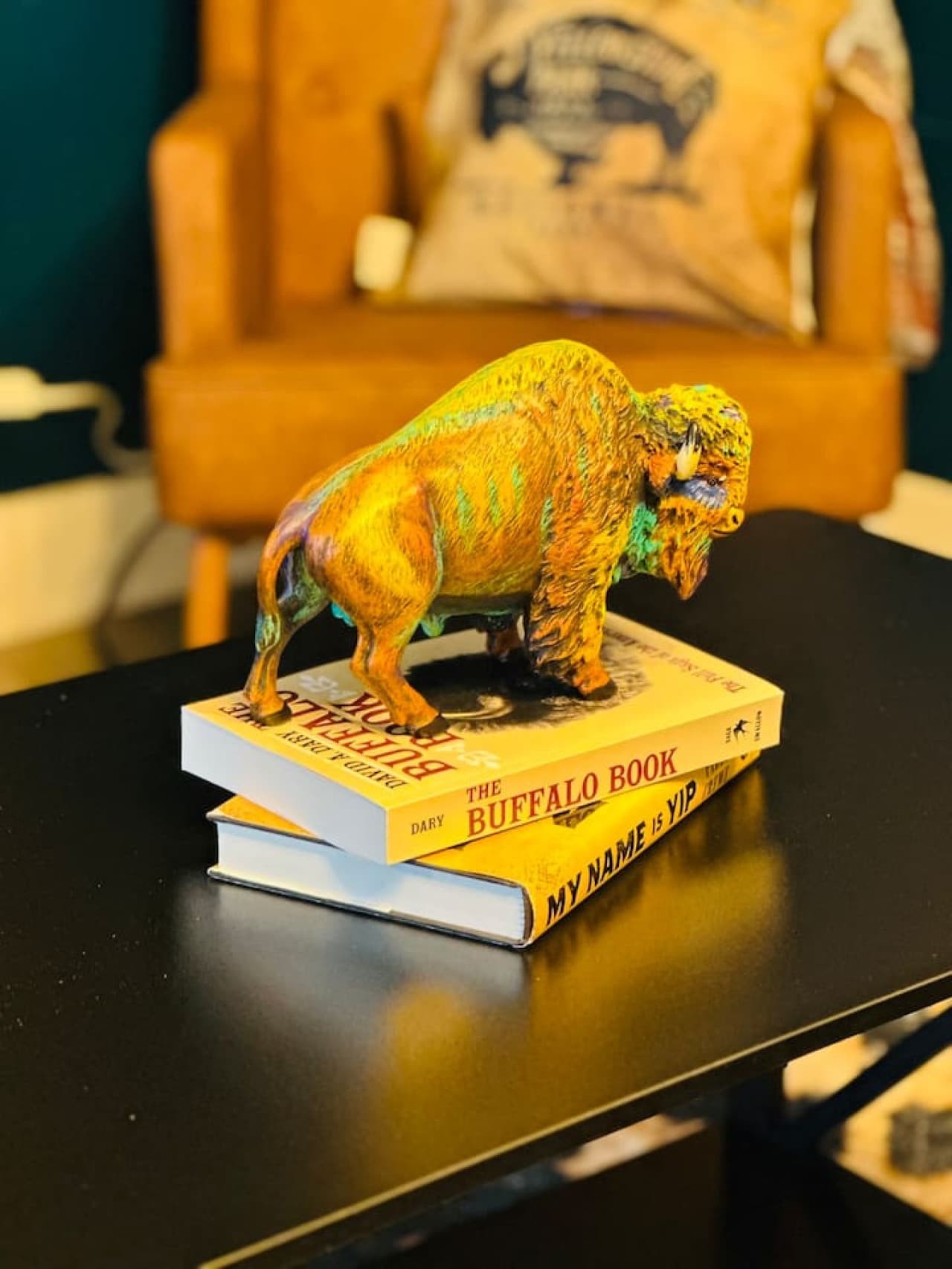 A vibrant buffalo sculpture rests atop books celebrating the wild heart of the plains.