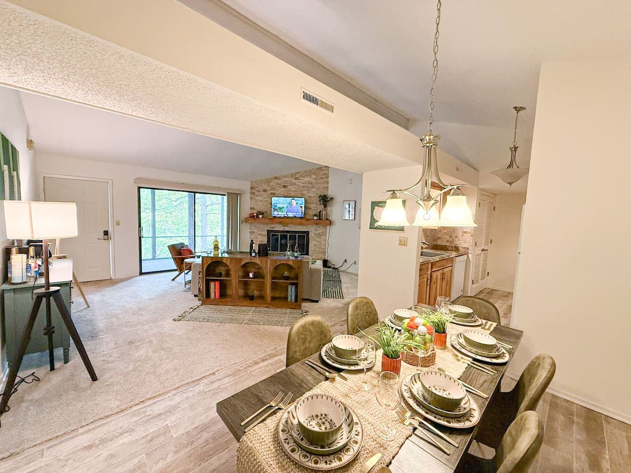This inviting home boasts an open-concept living space, featuring a cozy fireplace in the living room and a dedicated dining area perfect for entertaining. Large windows and a glass door offer abundant natural light and views of the surrounding green