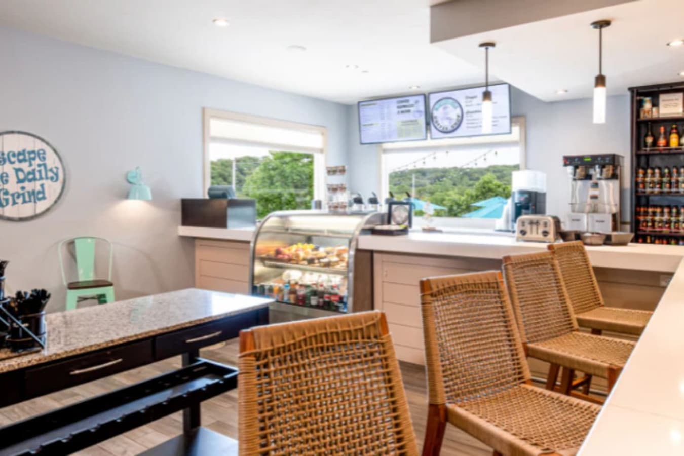 This bright and modern cafe space is ideal for a bustling coffee shop or quick-service eatery, featuring a well-equipped counter with a display case and ample seating. Large windows offer pleasant views, creating an inviting atmosphere for patrons.