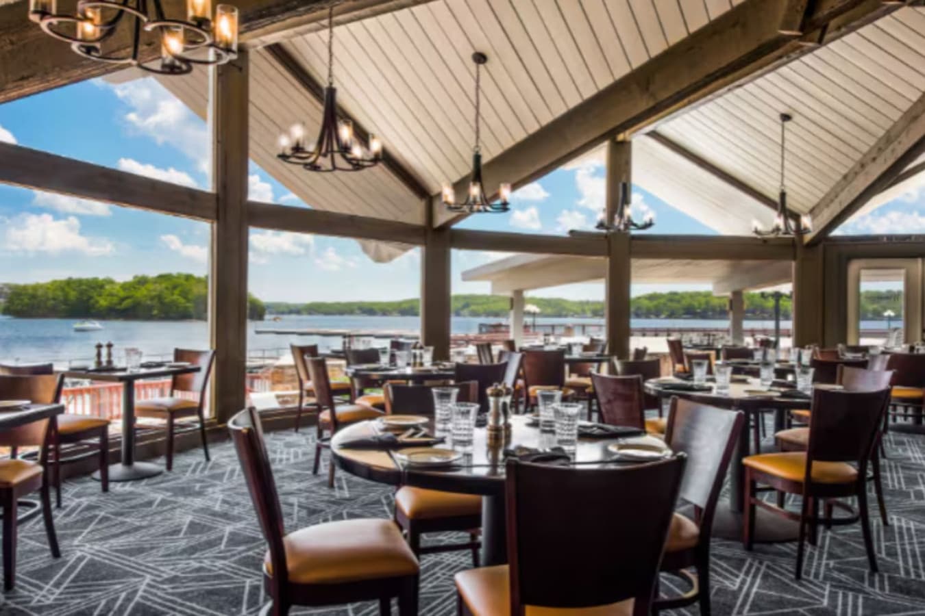 This exceptional lakeside dining venue boasts breathtaking water views through expansive windows, creating an inviting atmosphere for patrons. The spacious interior features vaulted ceilings with exposed beams and elegant chandeliers, offering a perf