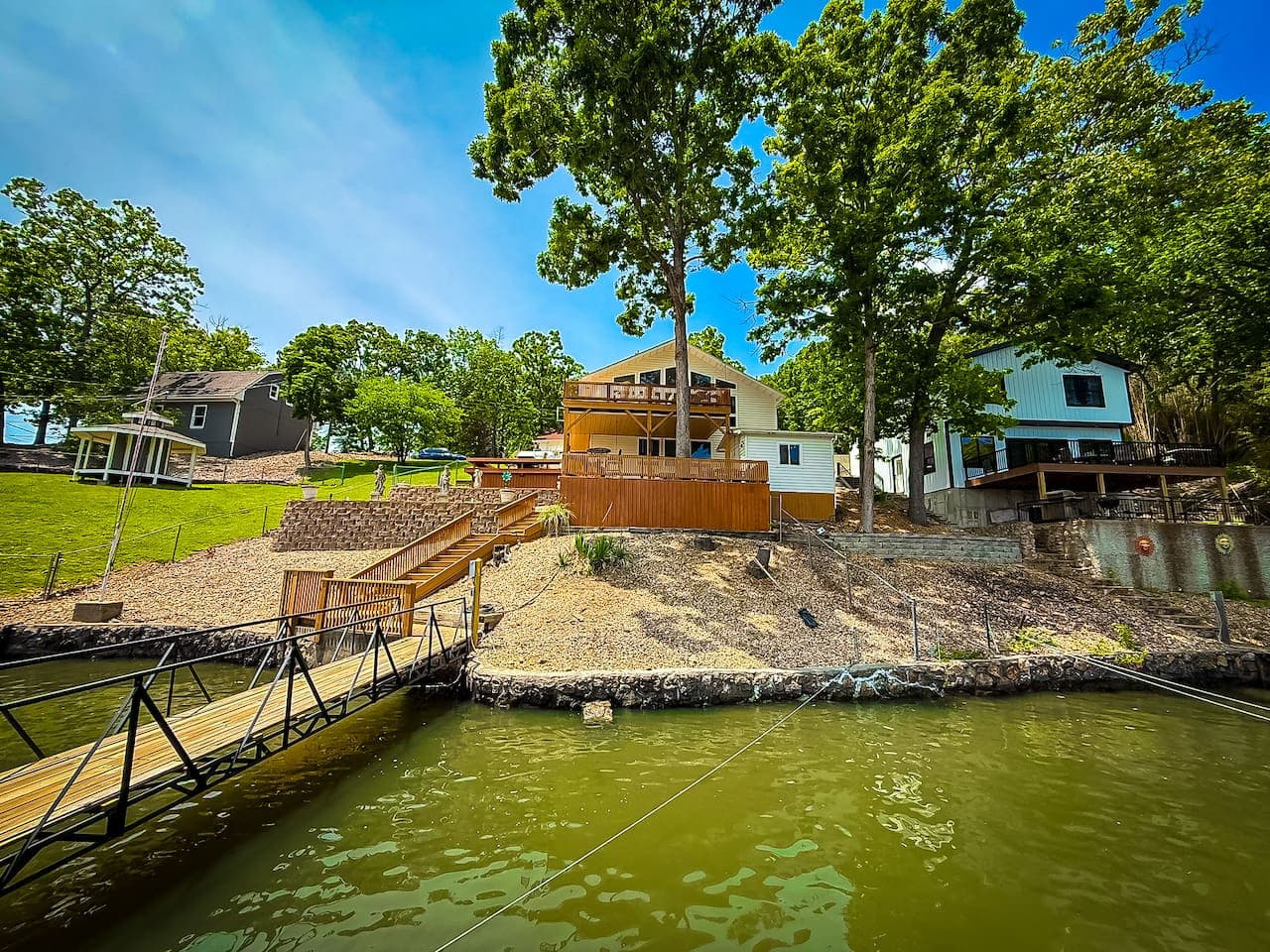 A tranquil lakeside retreat with a wooden dock, spacious deck, and cozy outdoor seating. Surrounded by lush trees, it offers serene waterfront views and outdoor adventure opportunities.