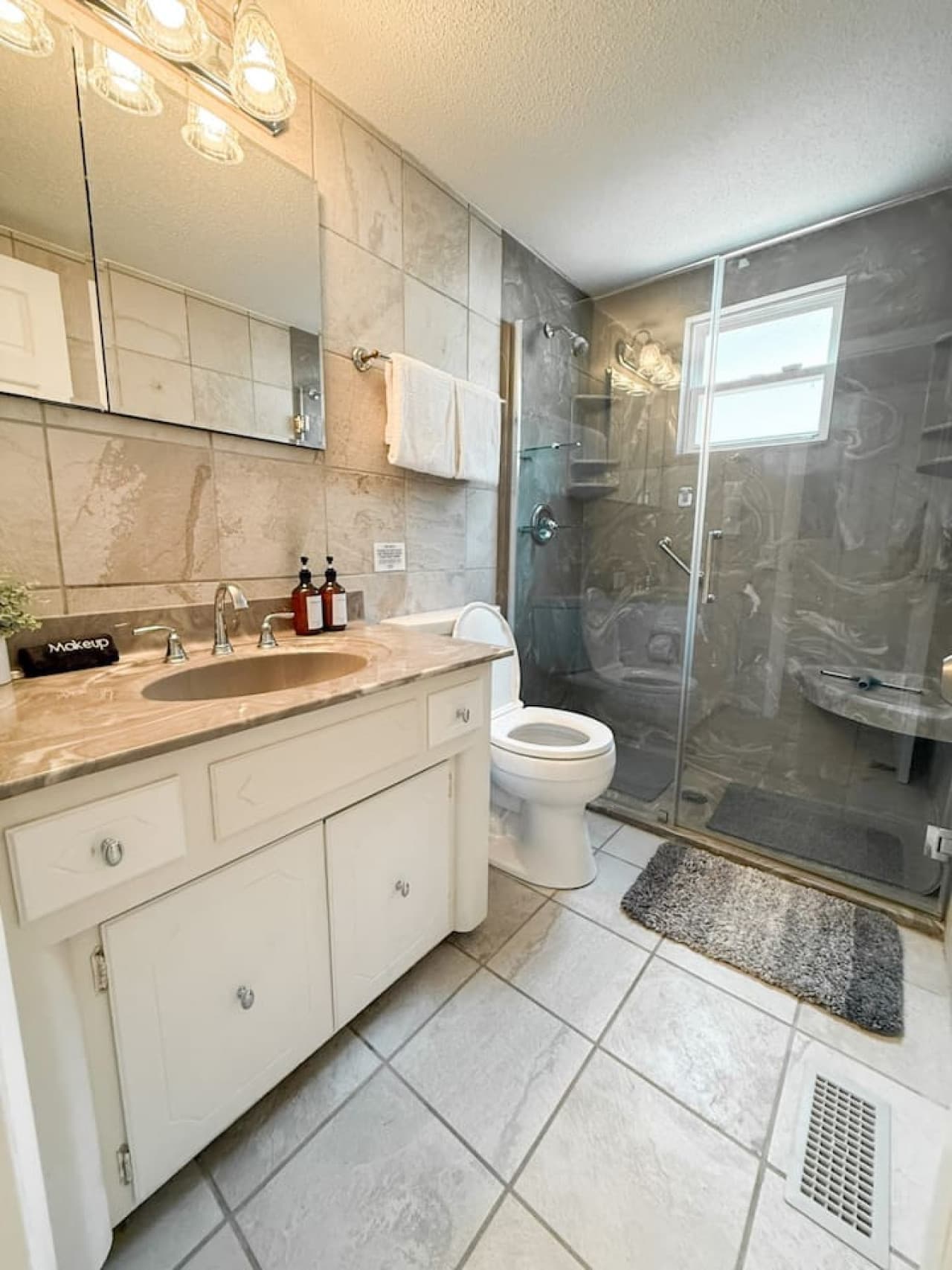 A sleek and modern bathroom featuring a walk-in shower with glass doors. accented with granite finishes.