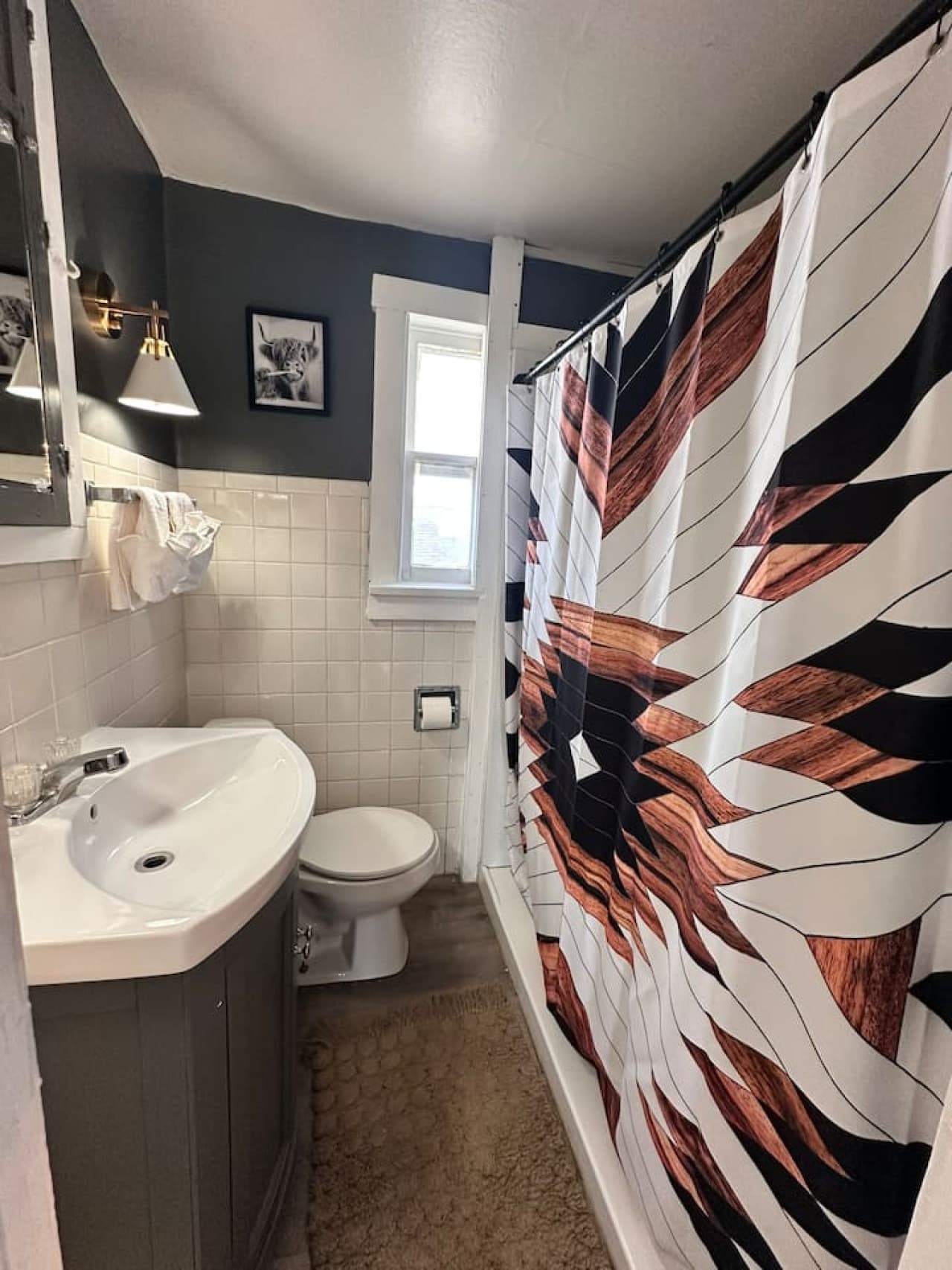 Custom shower curtain and cozy textures add personality to this compact bathroom.