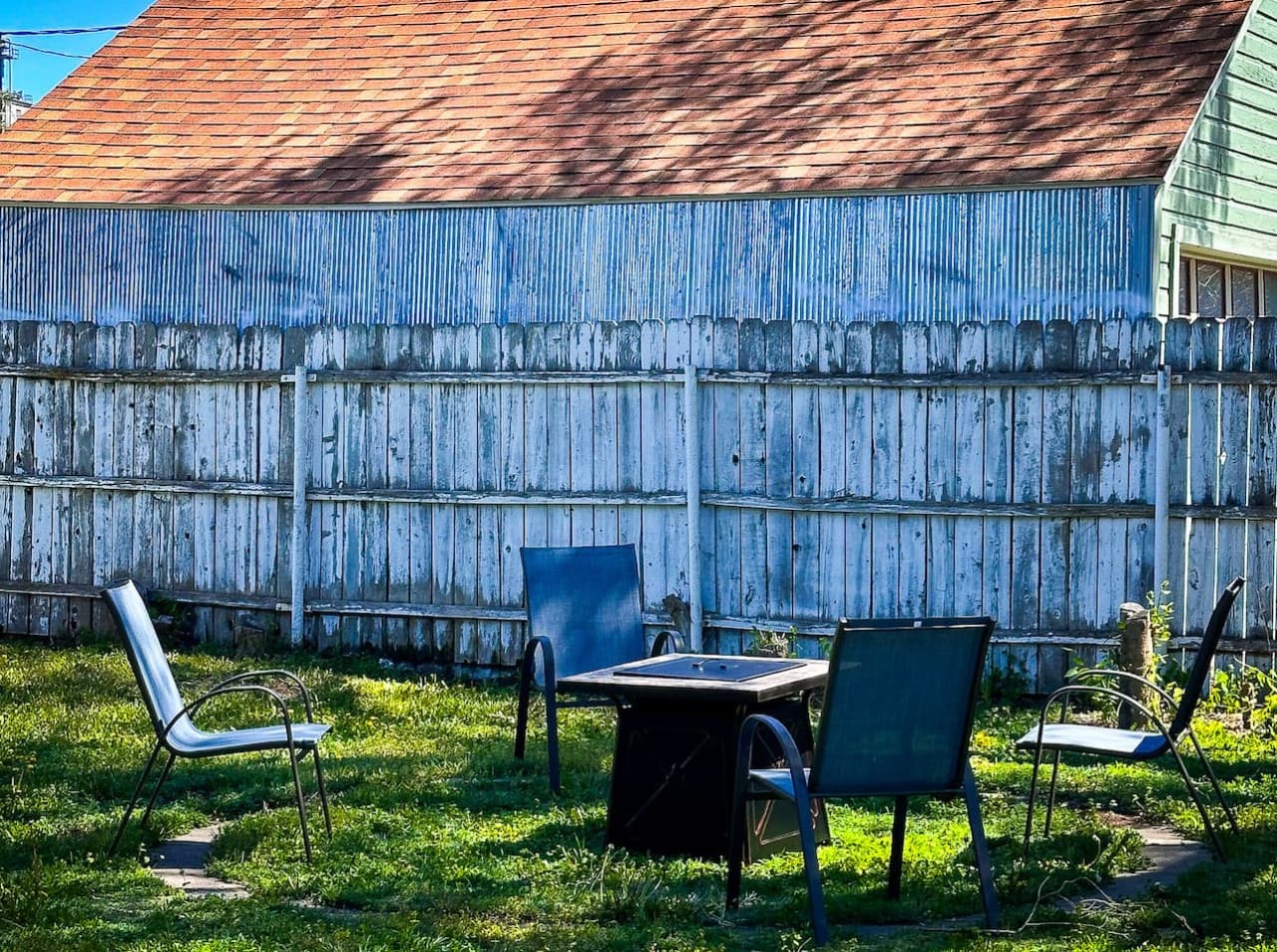 A charming outdoor space featuring a fire pit surrounded by four comfortable chairs, perfect for evening gatherings. The private fenced yard provides a cozy and secure area for relaxation and entertaining.