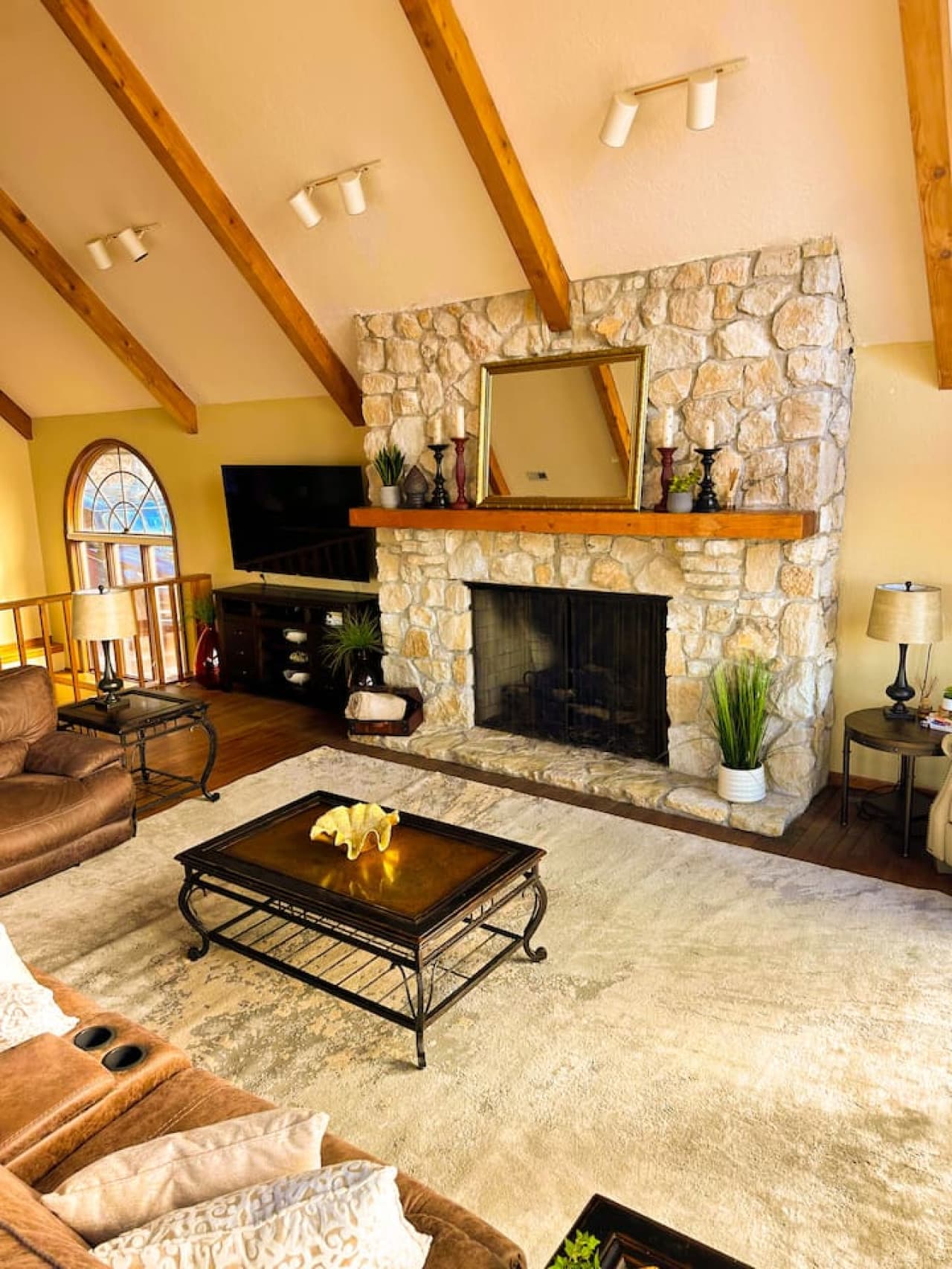 Relax by the grand stone fireplace in this warm and inviting living room with vaulted ceilings and rustic charm.