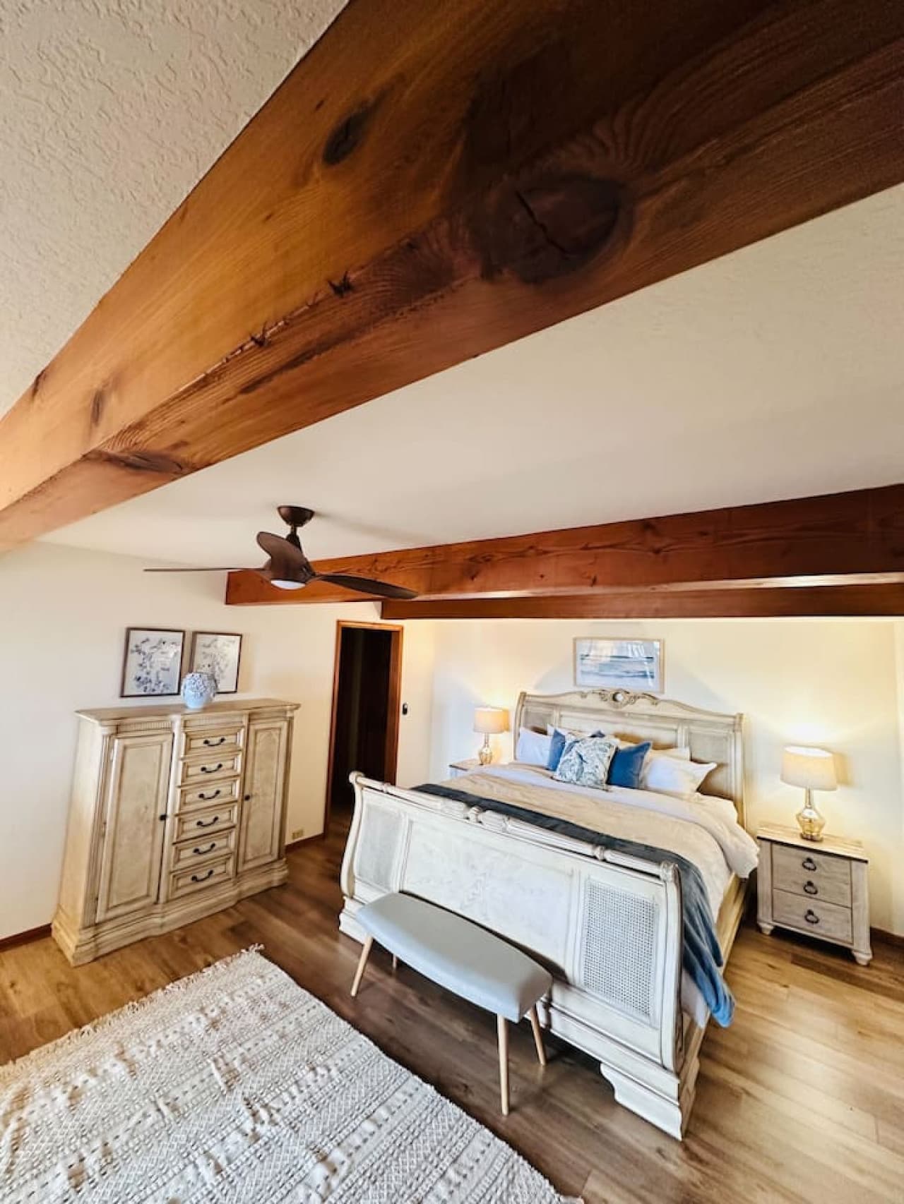 The king master suite combines rustic charm with modern comfort, featuring exposed wood beams and soft lighting.