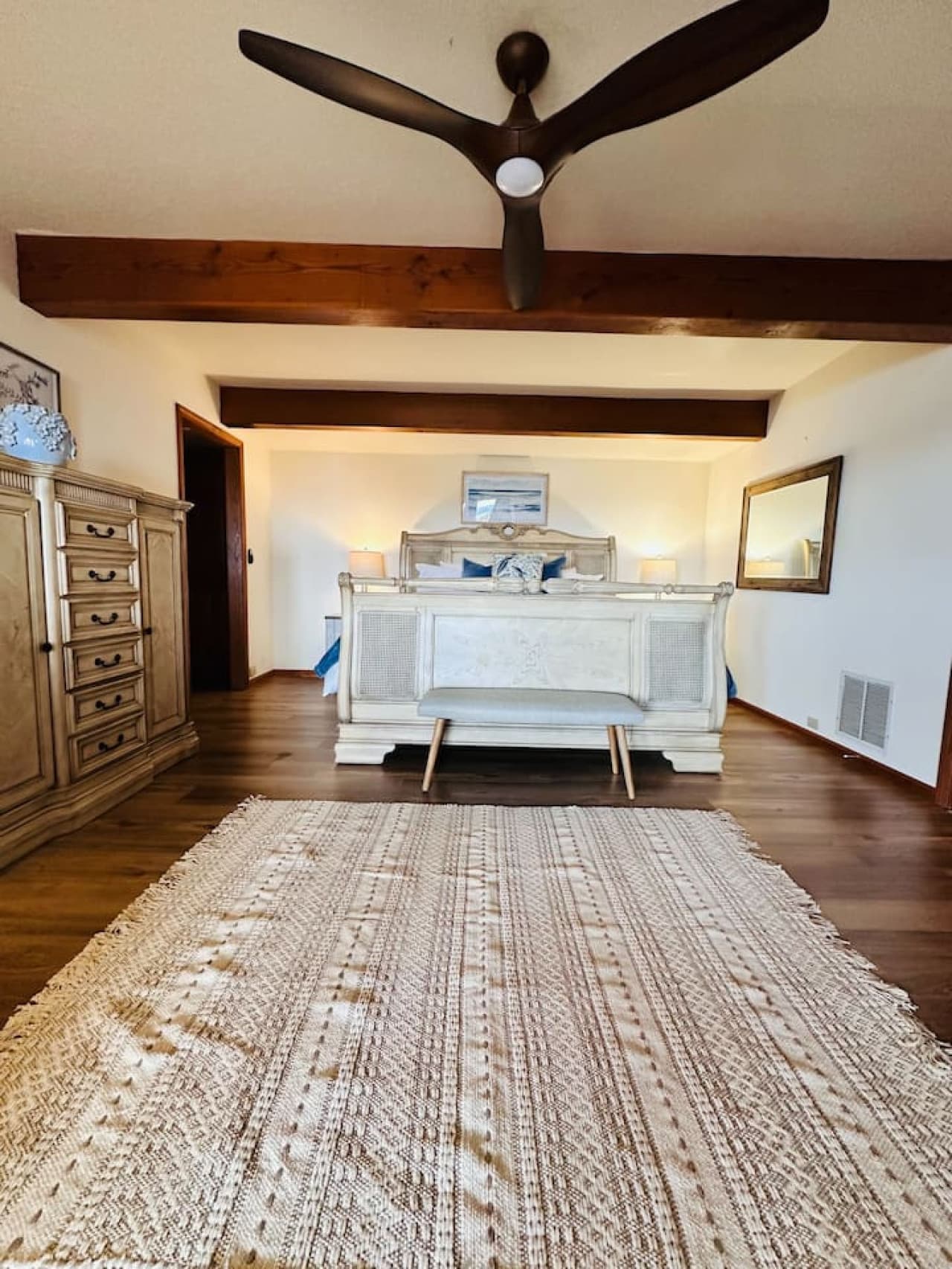Retreat to the king master bedroom suite, boasting rustic beams, warm wood flooring, and timeless furnishings.