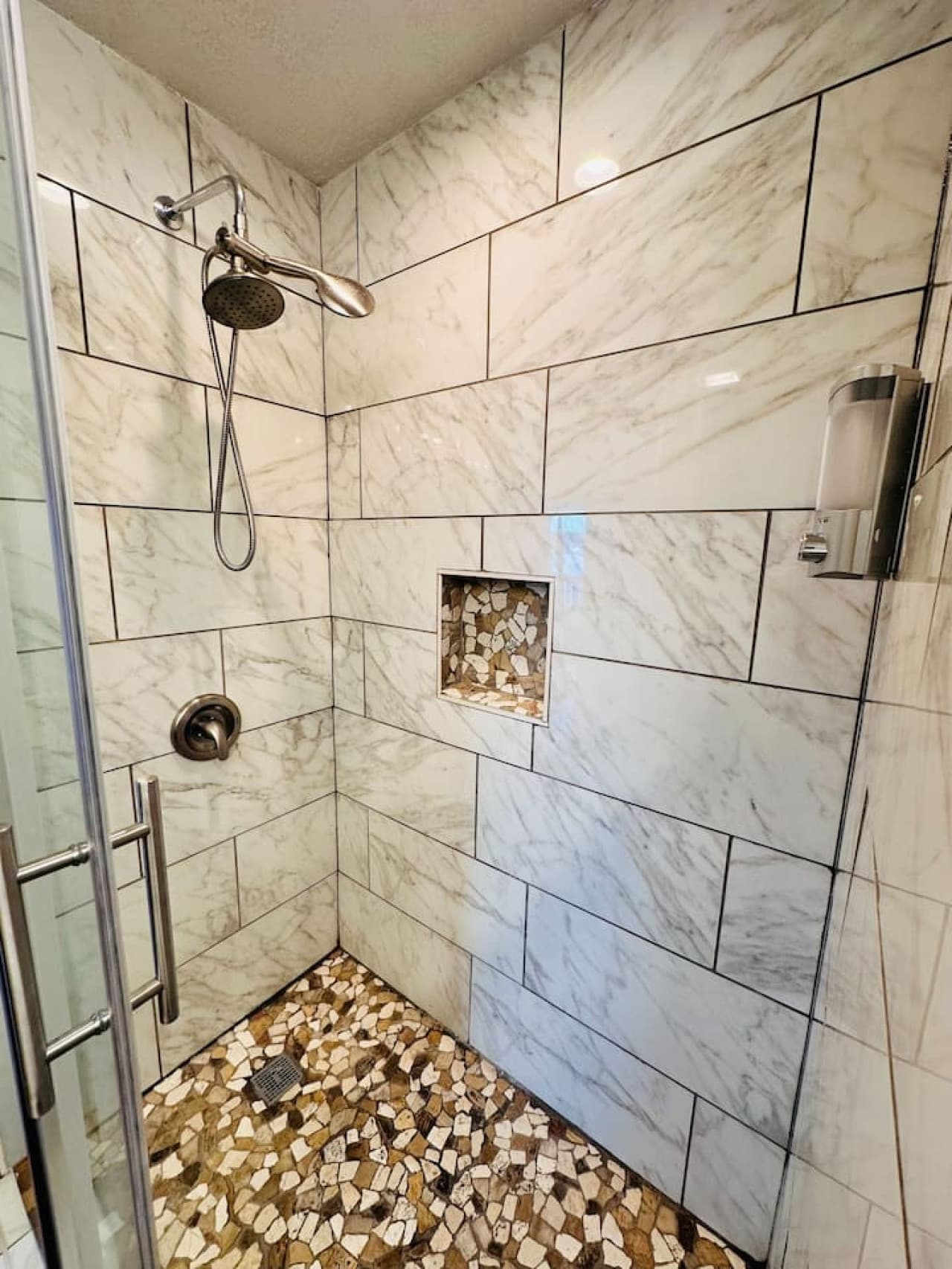 Enjoy a spa-like experience in this stunning walk-in shower with custom tile and built-in shelving.
