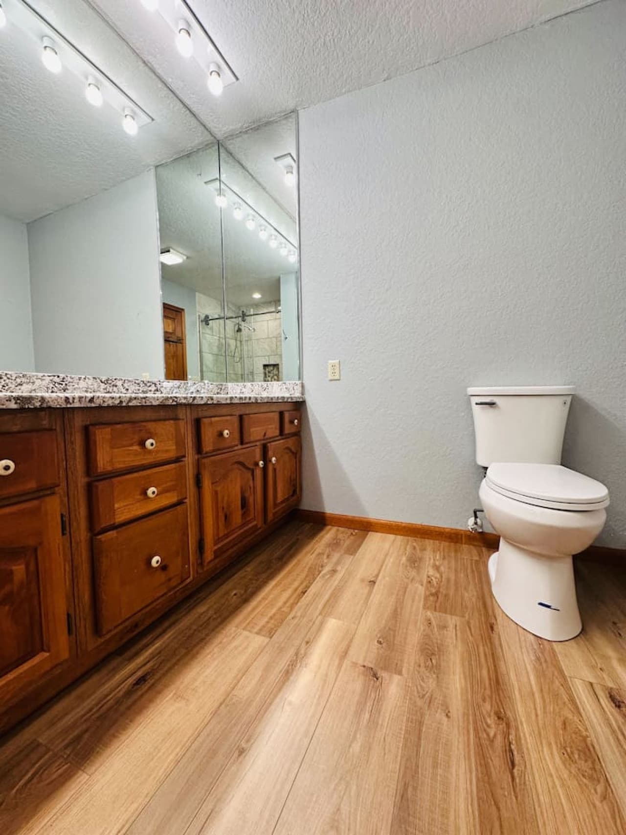 Granite countertops and natural wood cabinetry make this bathroom both functional and stylish.