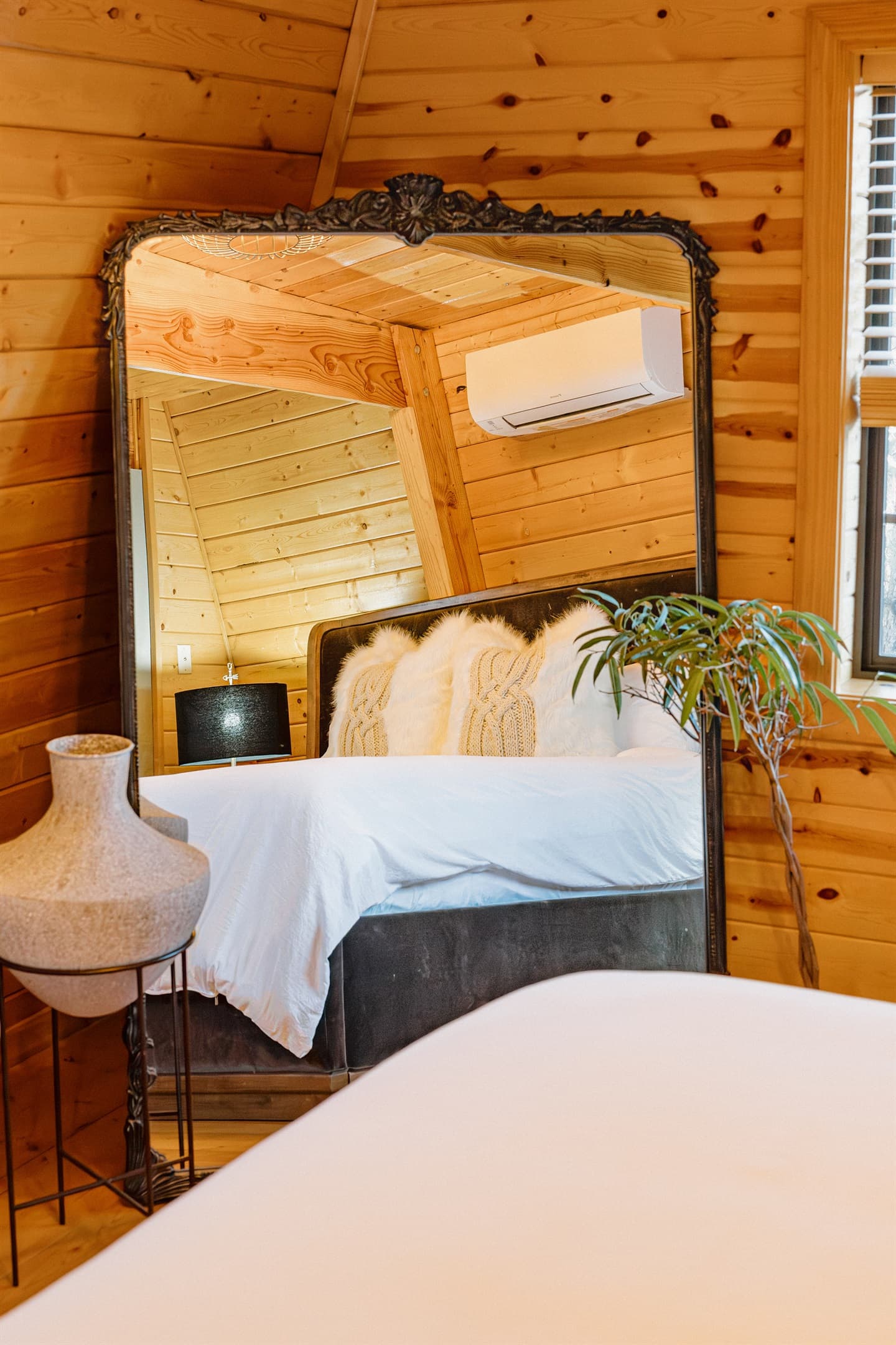 The iconic Anthropologie mirror adds gothic elegance to the bedroom at Poppywood Pines. This stylish Show Low A-frame features curated decor and plush bedding, creating a cozy retreat after exploring White Mountains hiking trails, fishing, and skiing.