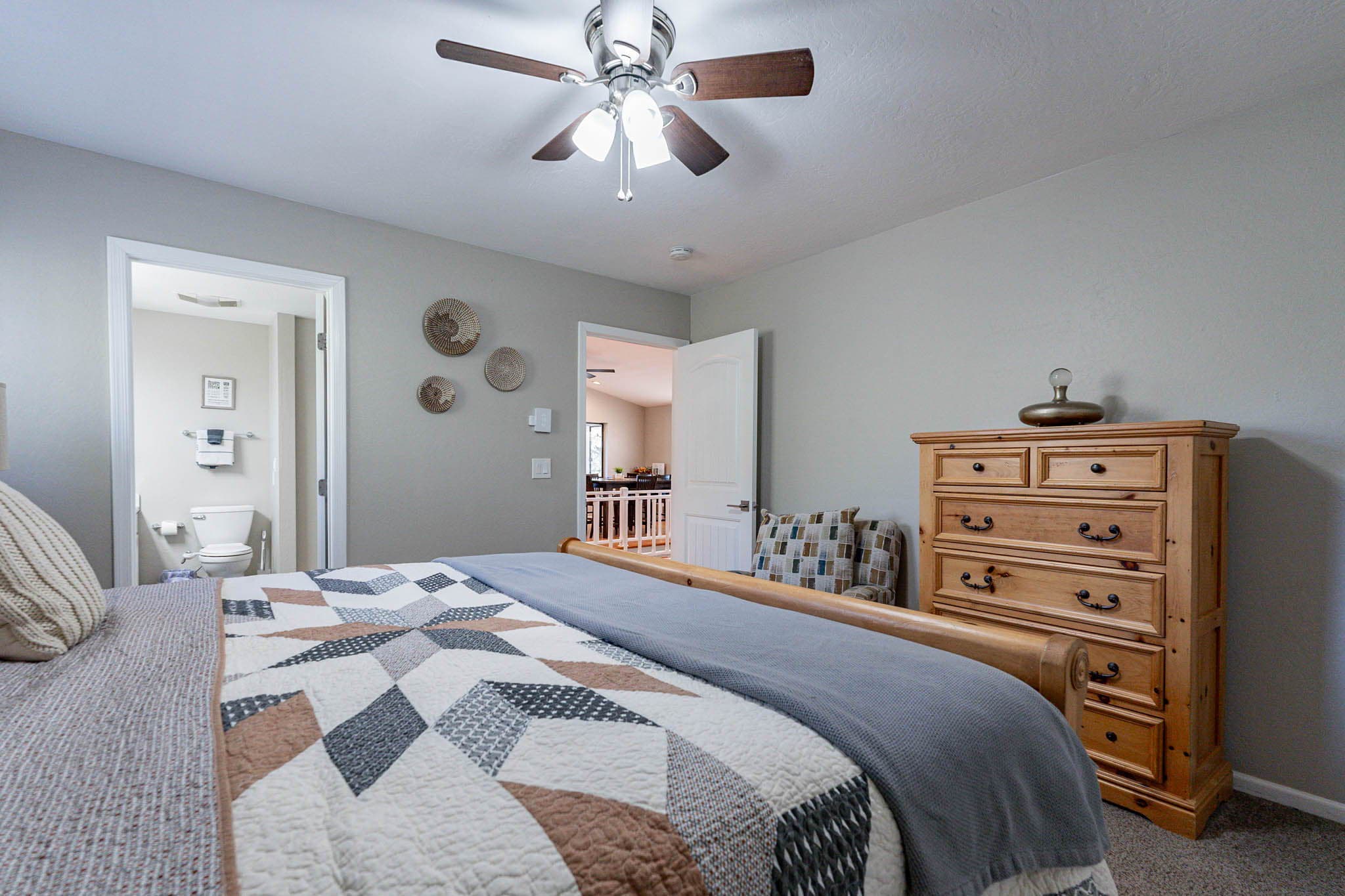 Tranquil upstairs primary bedroom with ceiling fan and ensuite.