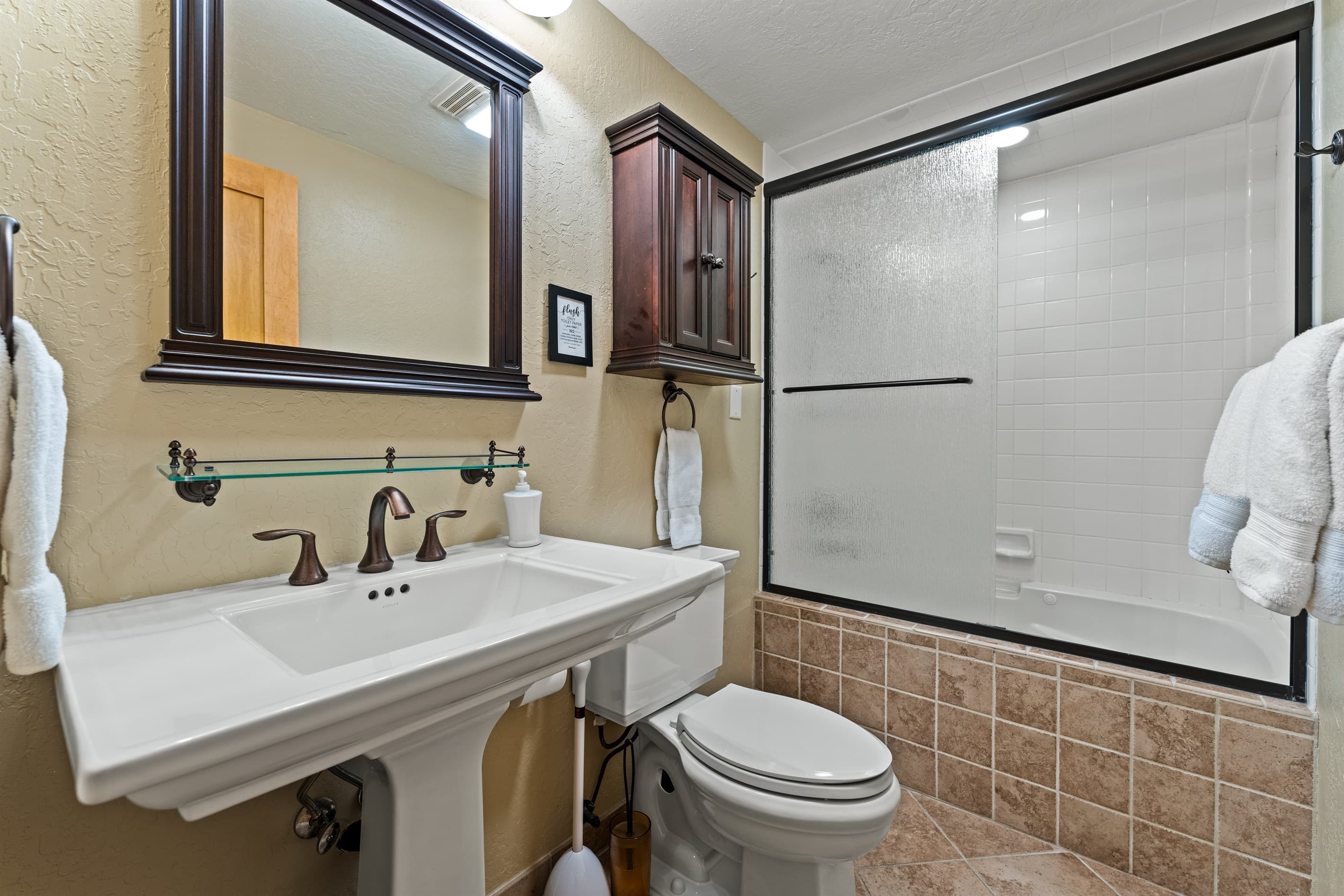 The downstairs primary bathroom features a single vanity and a tub/shower combo. Essentials such as toilet paper, hand soap, shampoo, conditioner, and body wash are provided for your convenience.