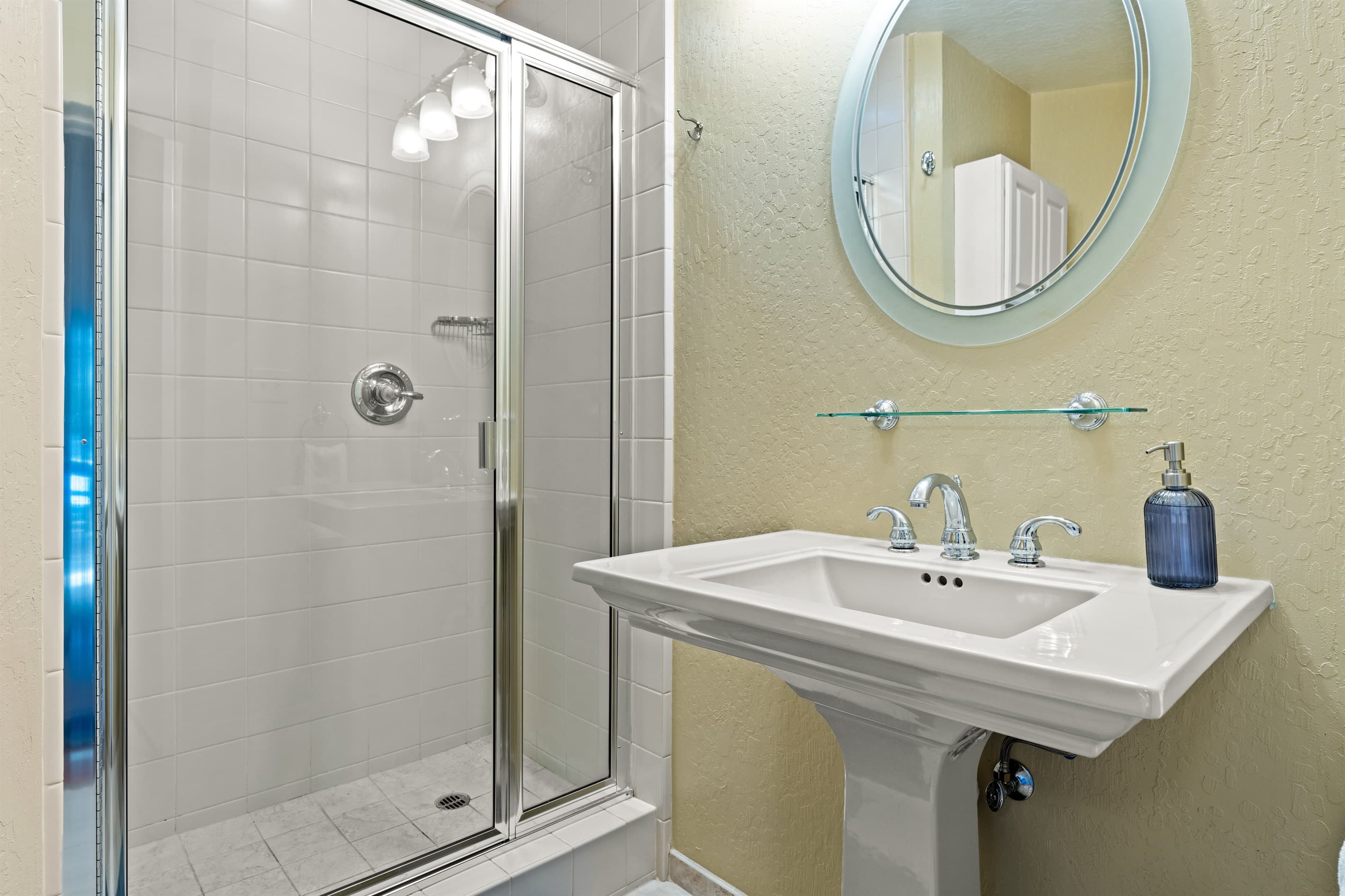 Upstairs primary bathroom features a single vanity and a walk-in shower. Essentials like toilet paper, hand soap, shampoo, conditioner, and body wash are provided for your convenience.