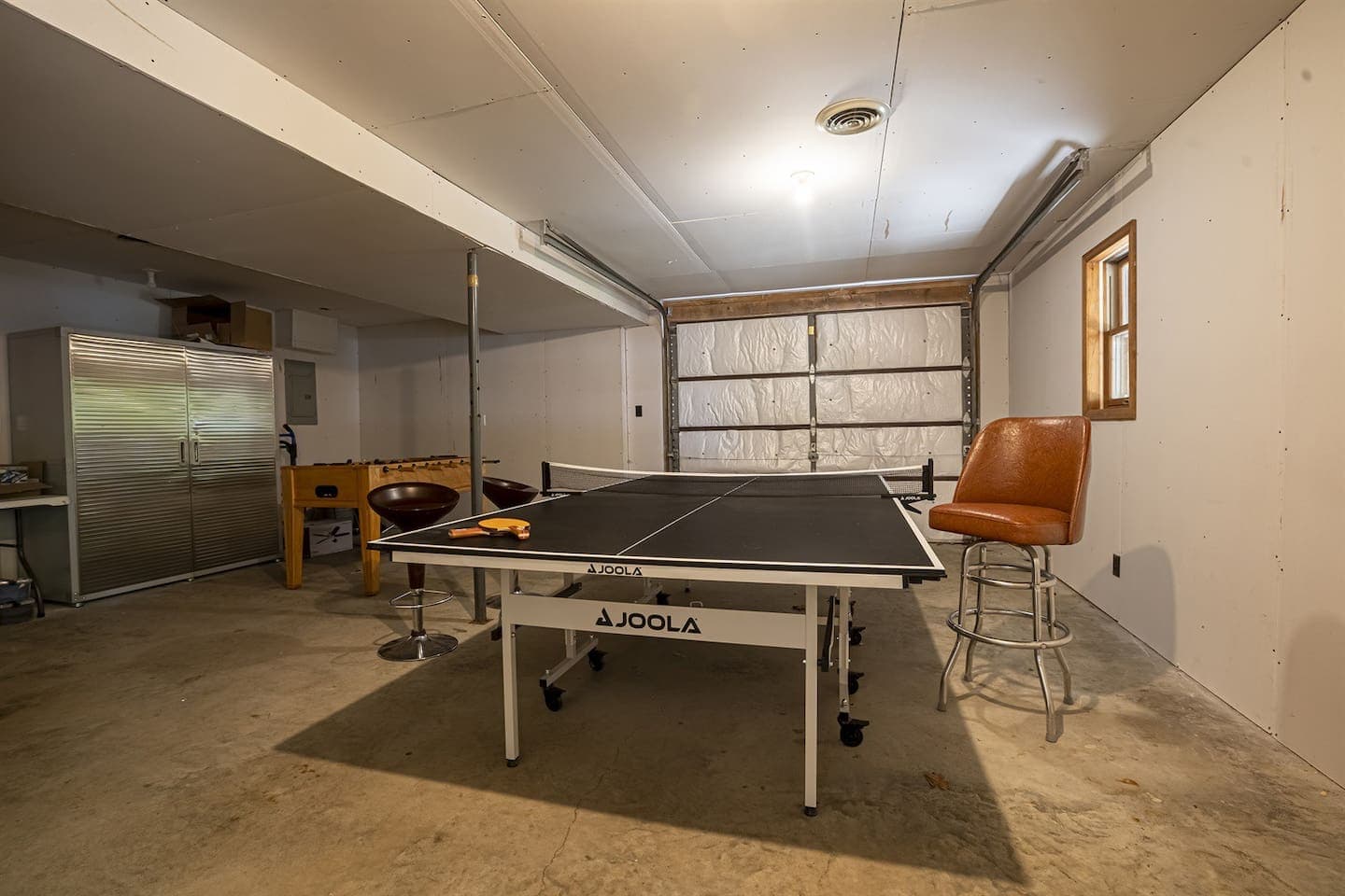 A ping pong table and a refrigerator in a garage.