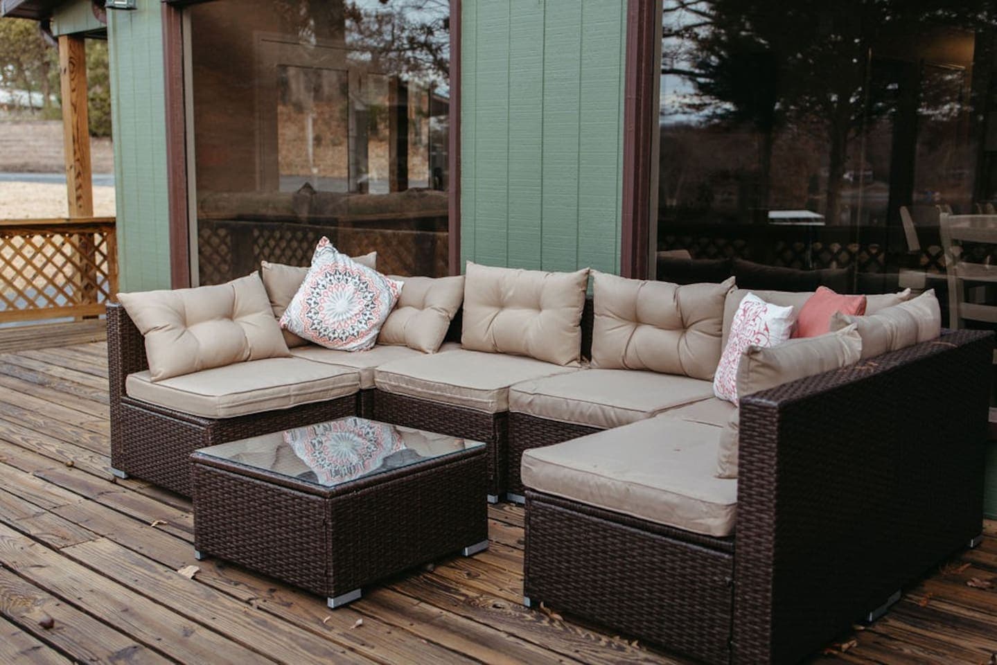 A cozy brown wicker sectional couch on a wooden deck, perfect for relaxing outdoors.