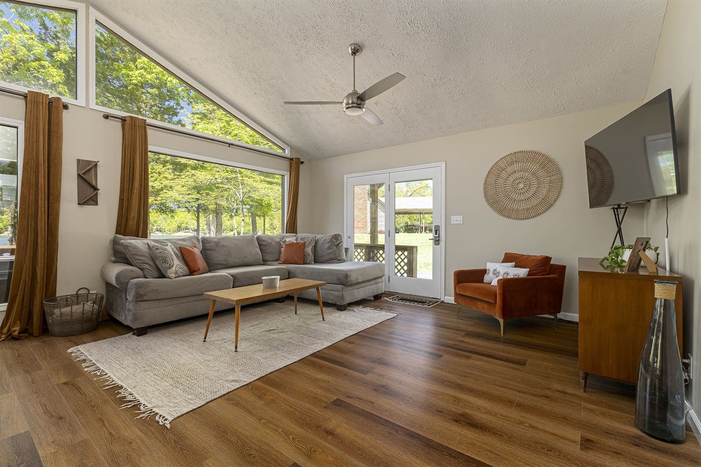 A cozy living room with wooden floors and a ceiling fan.