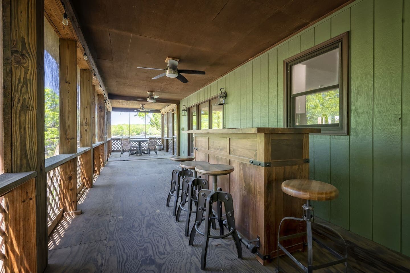 A porch with a bar and stools, perfect for relaxing and enjoying drinks outdoors.