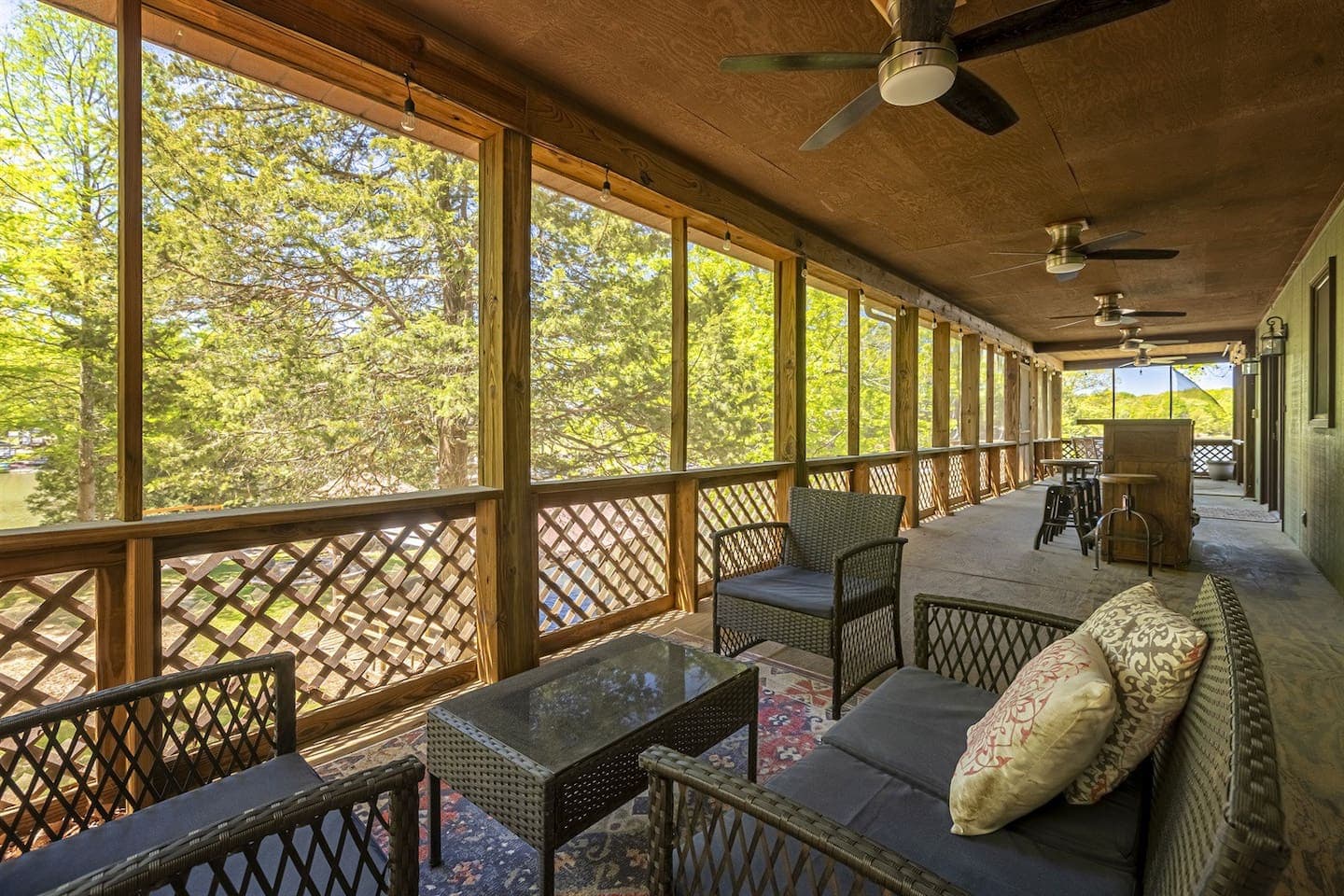 A cozy screened porch with wicker furniture and a ceiling fan, perfect for relaxing and enjoying the outdoors.
