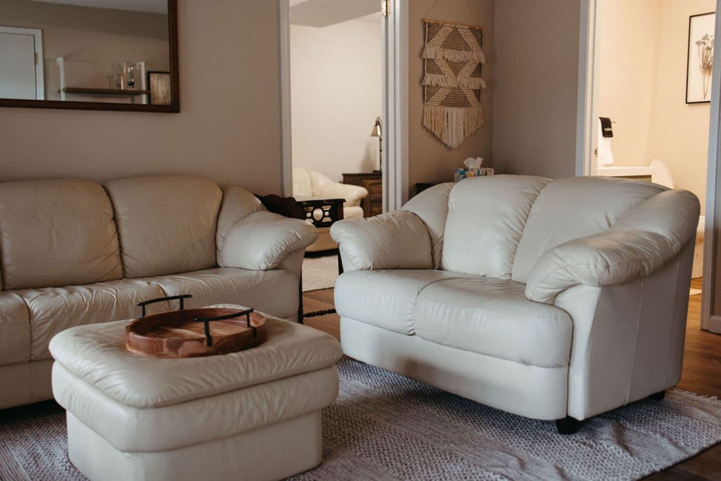 A modern living room with two white leather couches and a white ottoman.