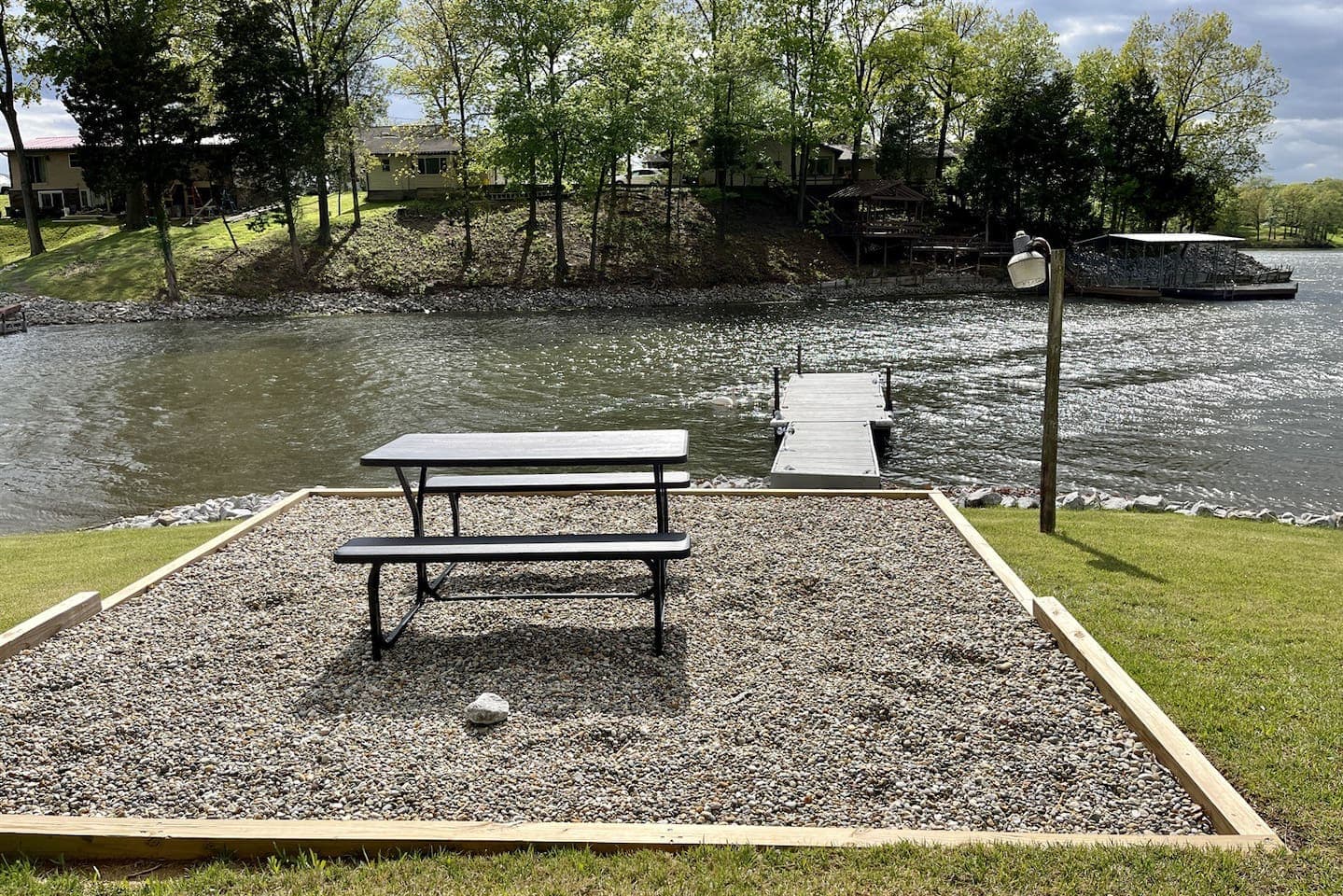 A serene lake view with a picnic table and a dock, perfect for enjoying a peaceful outdoor meal.