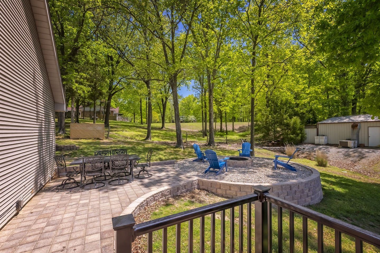 A cozy outdoor patio nestled in the woods, featuring a fire pit surrounded by chairs.