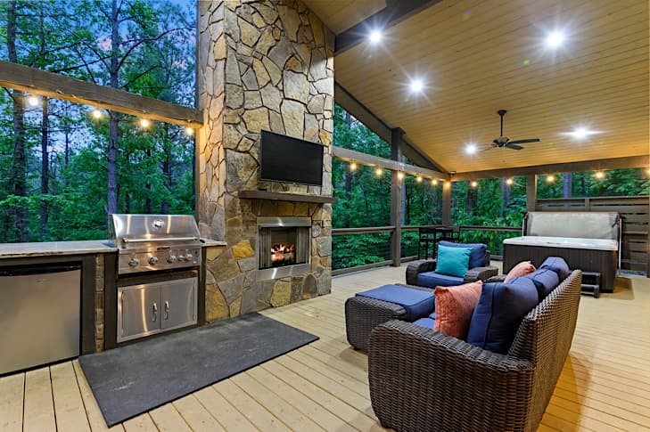 Spacious back porch with comfortable seating, built-in grill, mini fridge and fireplace