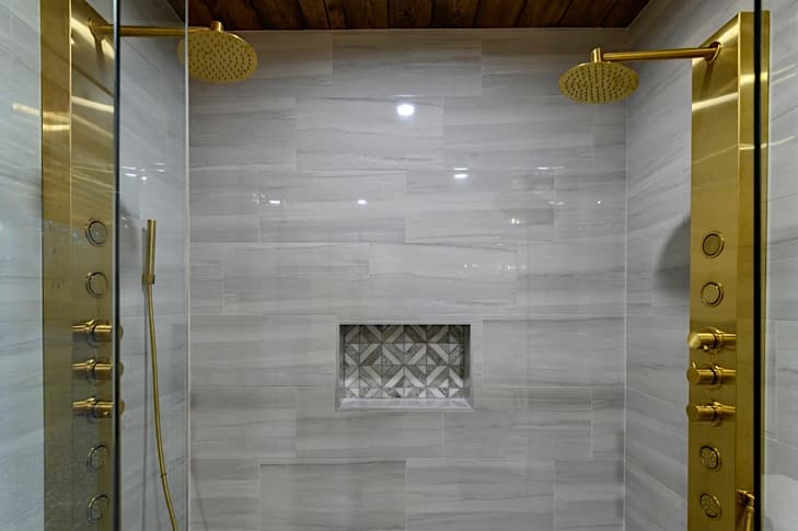 Large tiled walk-in shower has dual shower heads, body jets and rain head