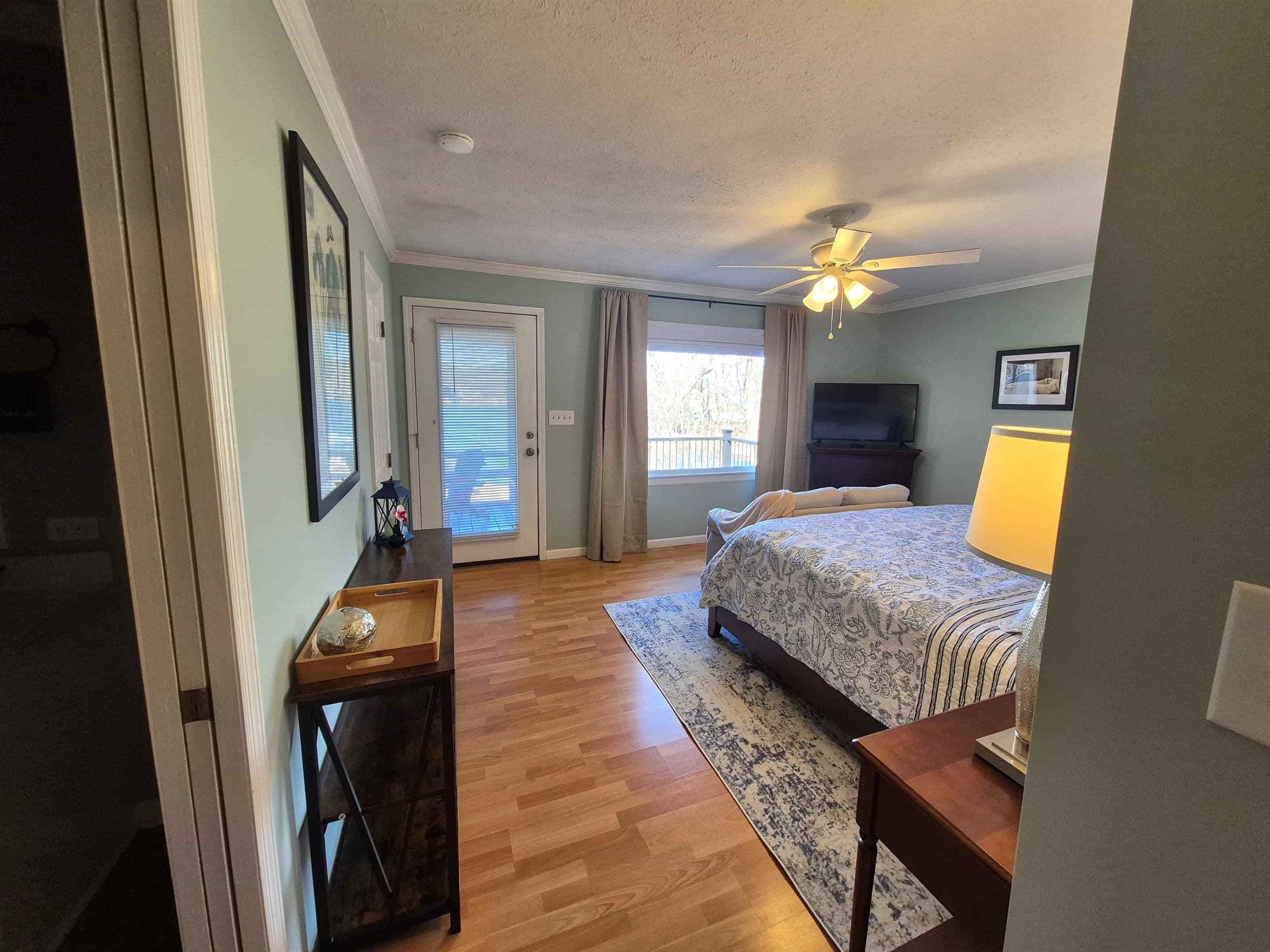 Master bedroom view with electric fireplace for year round use, small couch, king bed and direct access to private deck area and shared screened in porch
