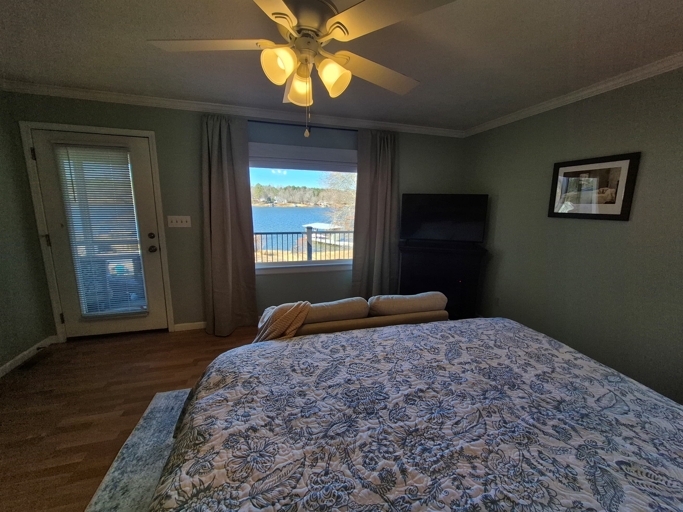 View from the bed in the master bedroom view with electric fireplace for year round use, small couch, king bed and direct access to private deck area and shared screened in porch