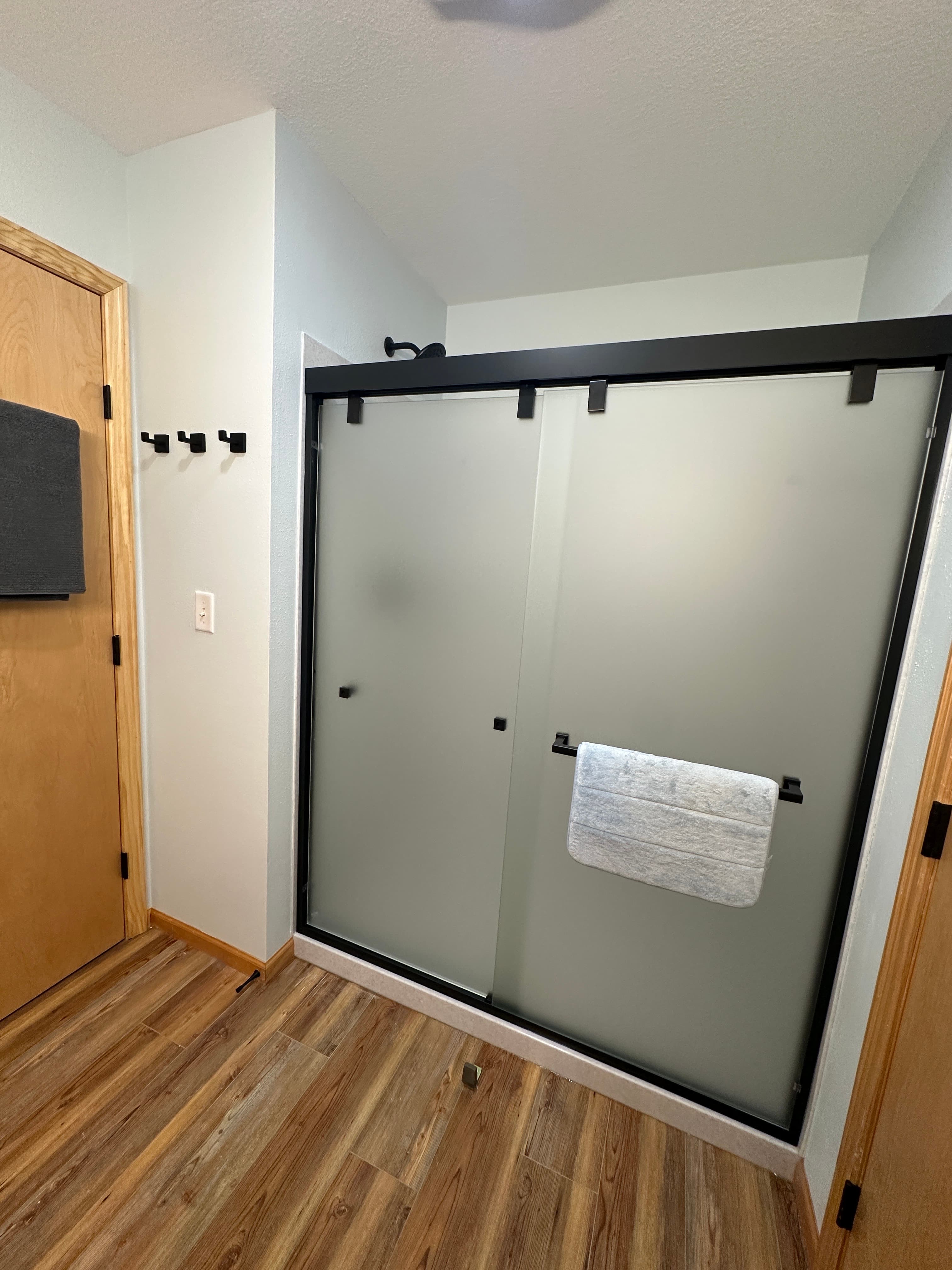 First-floor bathroom with a new walk-in shower, frosted glass doors, and overhead heat light—offering both style and extra comfort after a day outdoors.