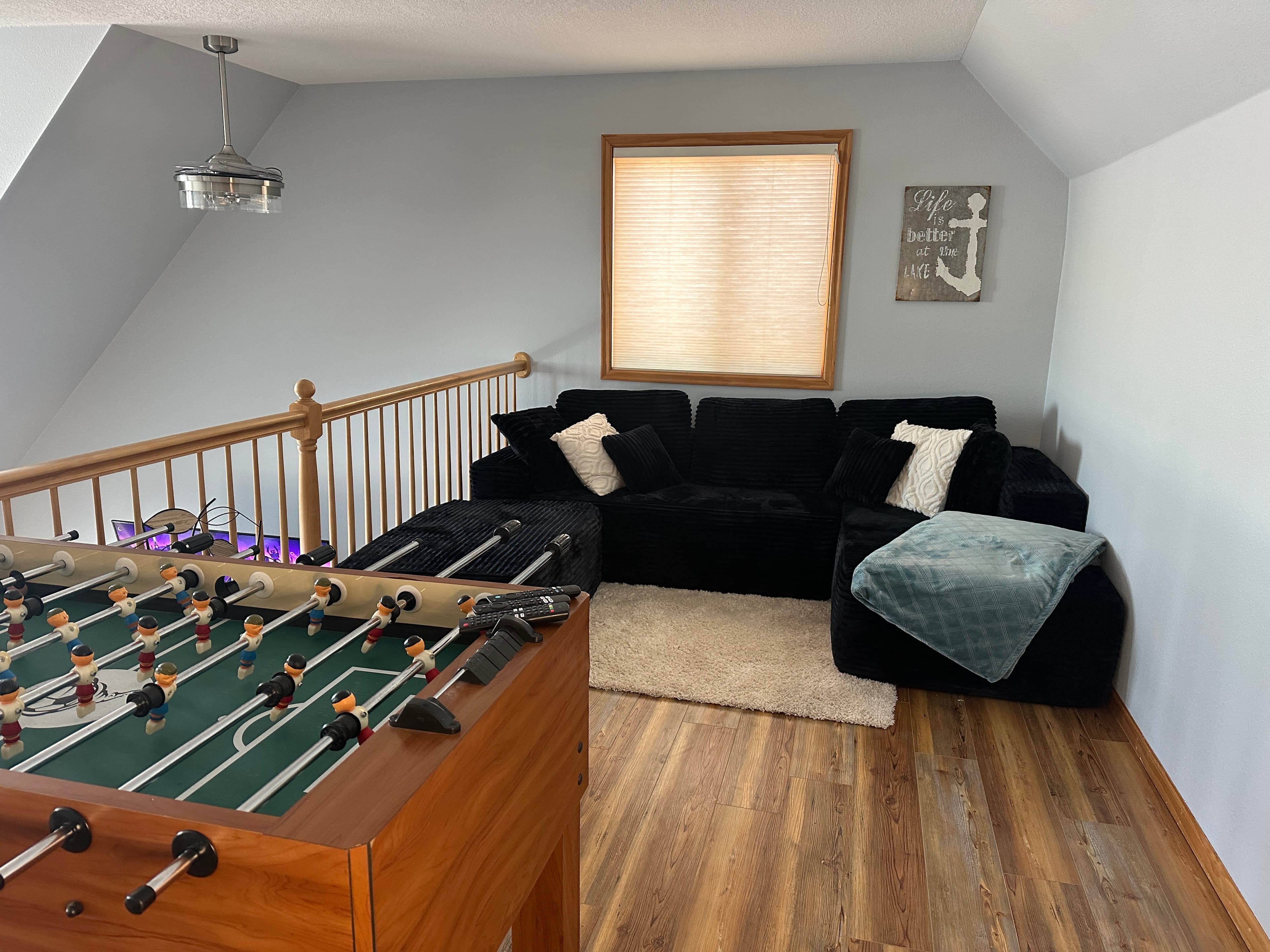 Loft entertainment area with foosball table, TV, and ultra-soft sectional couch—ideal for relaxing or playing.