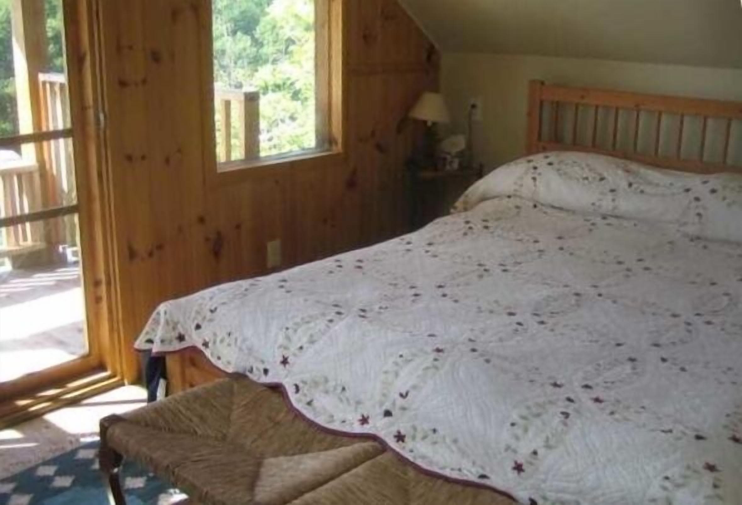 airconditioned guest cottage bedroom leads to covered balcony with lake view