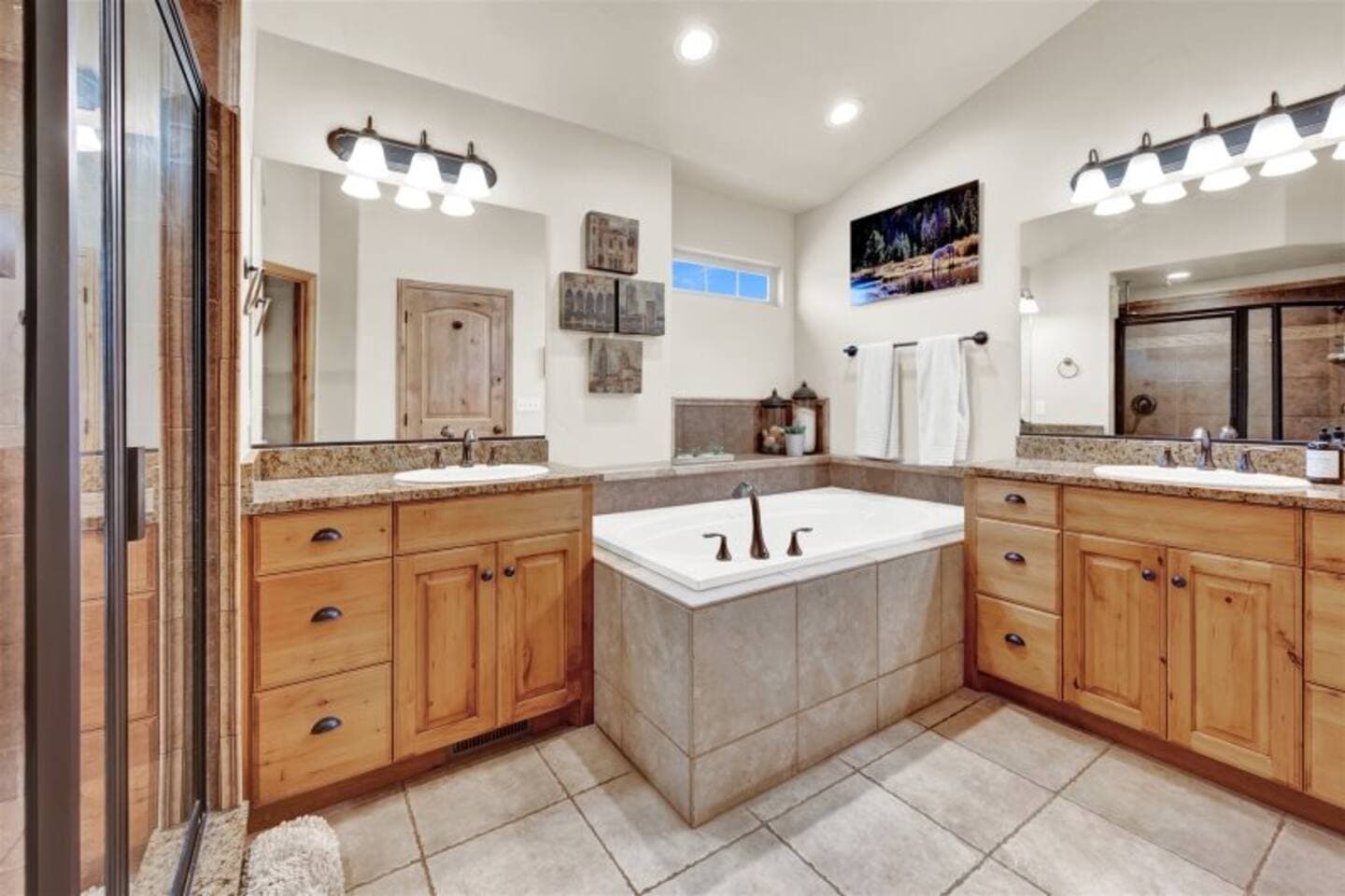 Spa-like primary bathroom featuring a deep soaker jetted tub, a walk-in glass shower,  and double vanities.